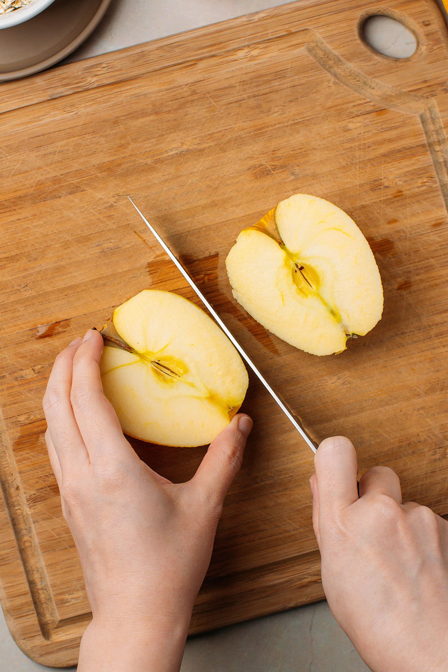 Slicing an apple in halves on a cutting board.