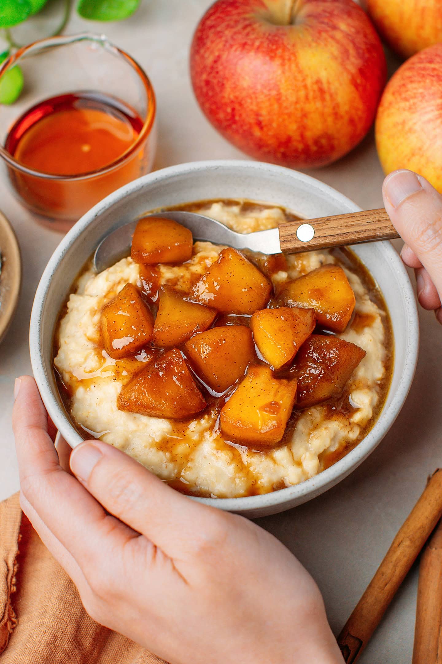 Holding a bowl of cinnamon oatmeal topped with tender apple chunks.