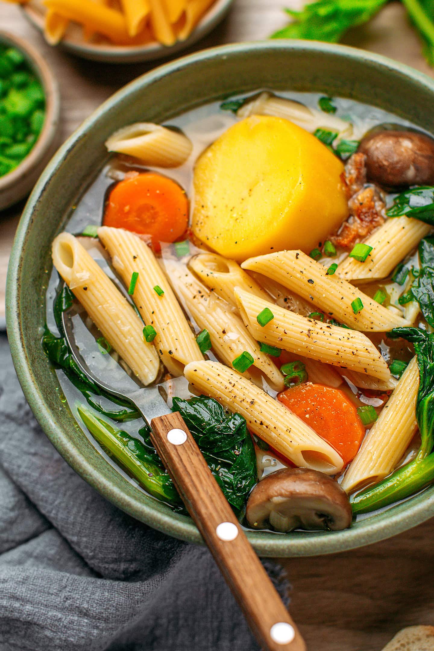 Close-up of a bowl of celery soup with pasta and green onions.