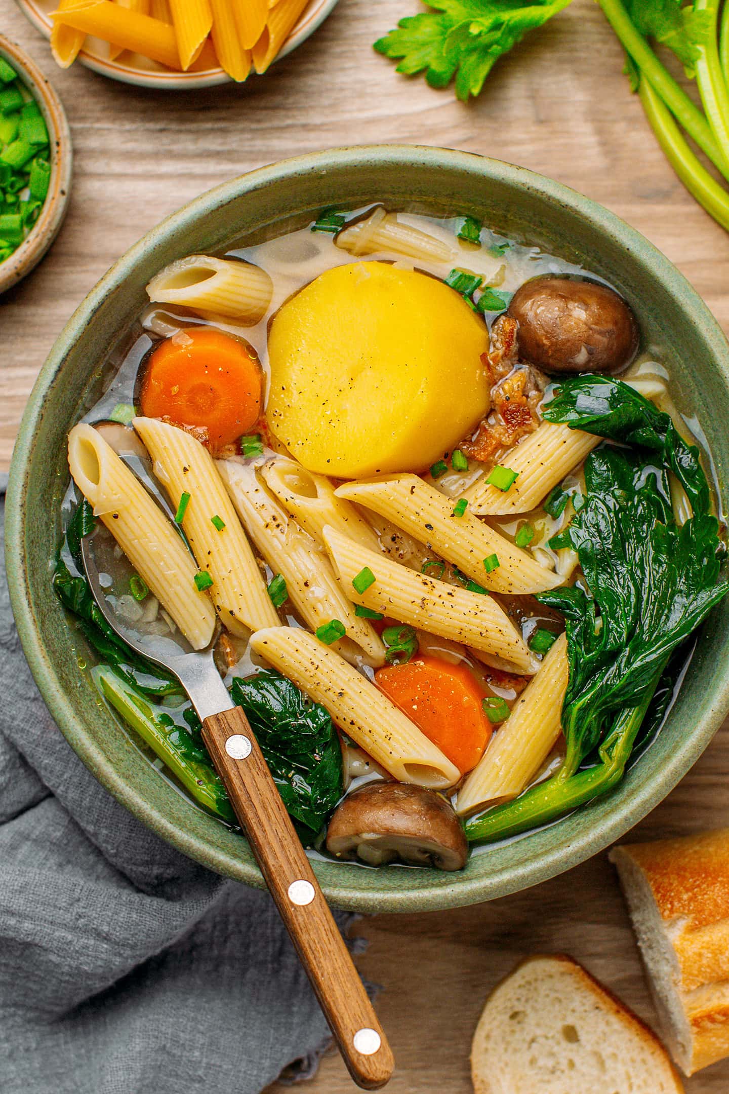Green bowl filled with vegetable soup and pasta.