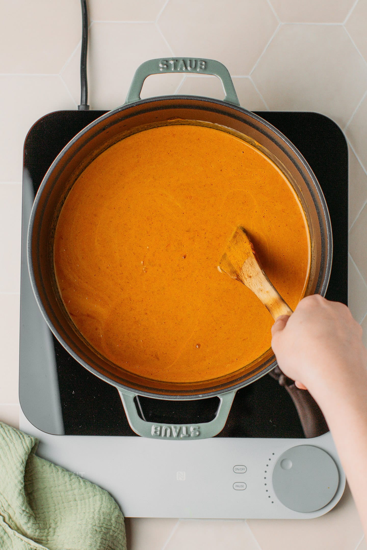 Stirring coconut milk with tomato sauce in a pot.
