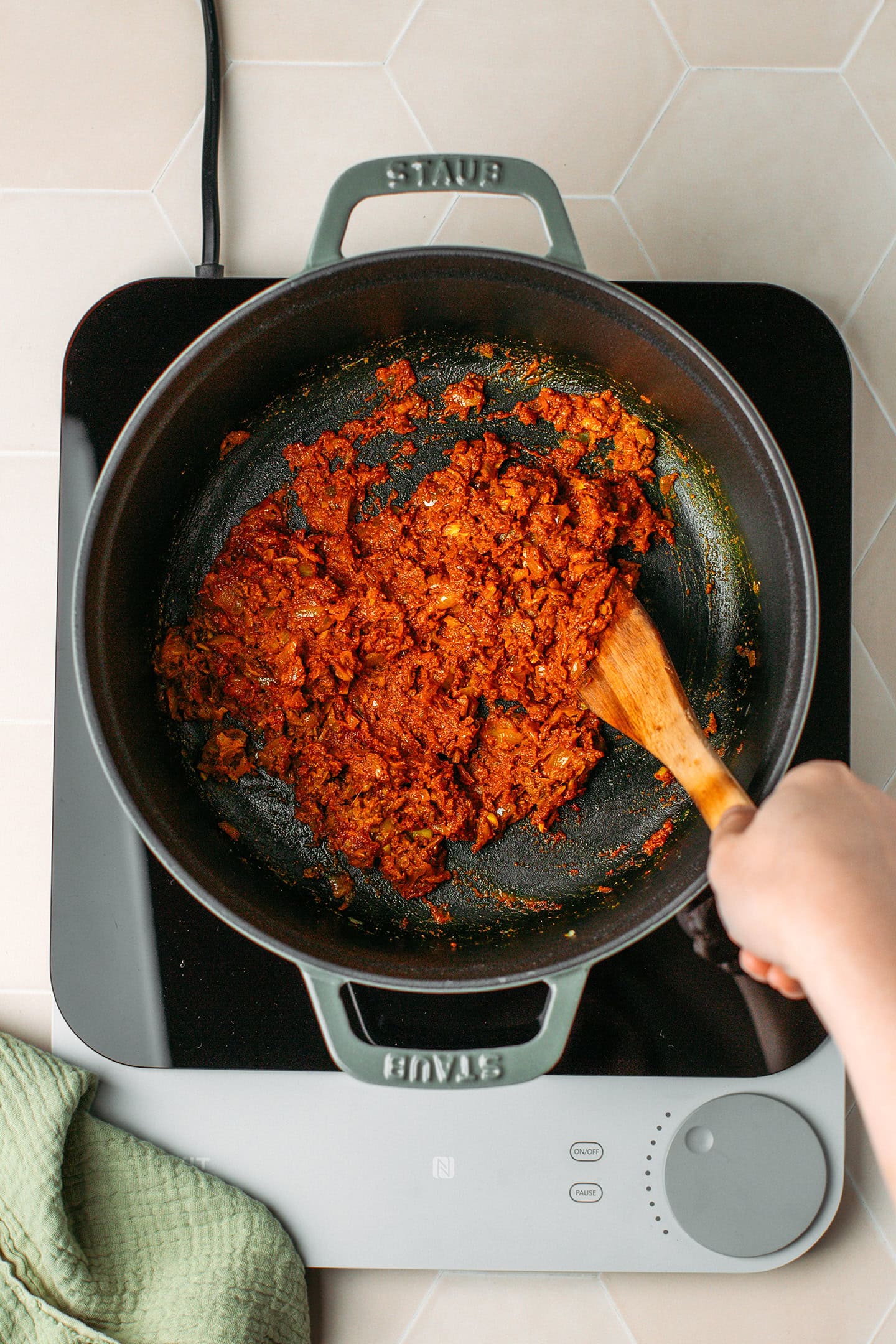 Stirring spices with diced onion, garlic, and ginger in a pot.