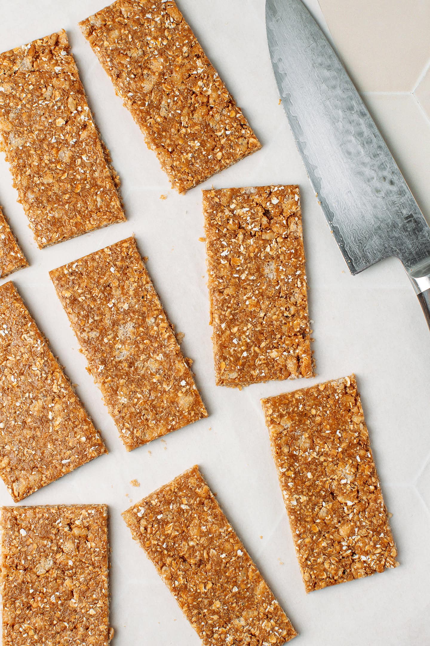 Rectangles of granola bars on a piece of parchment paper.
