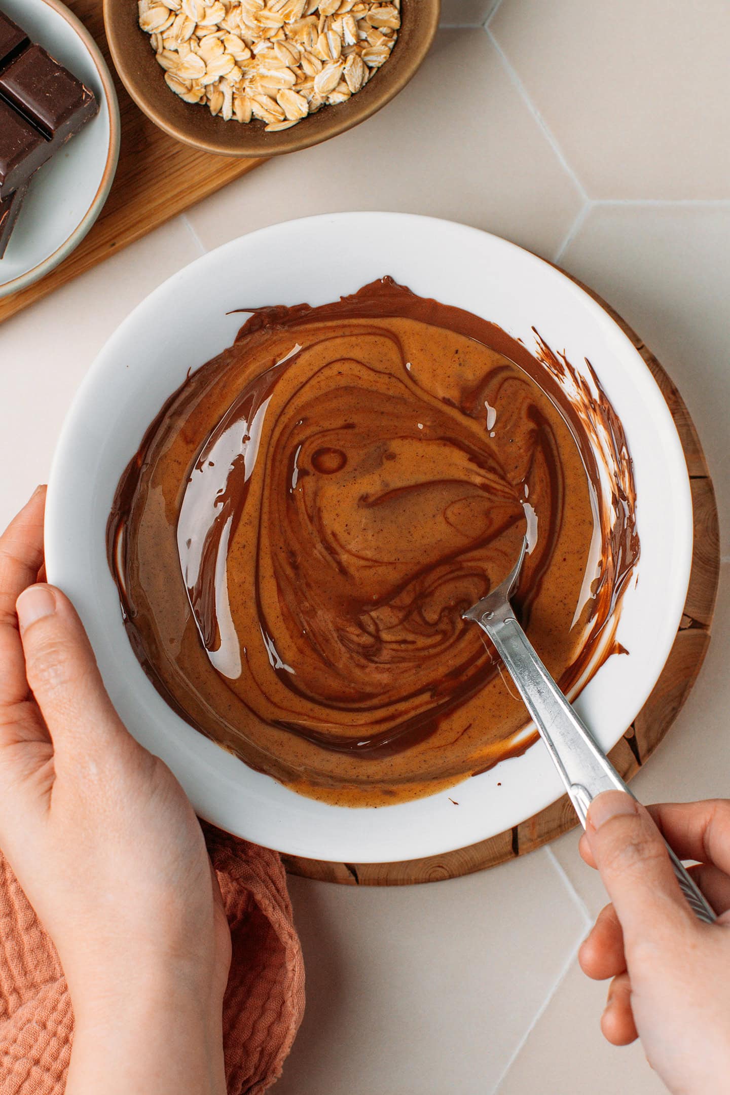 Mixing melted dark chocolate and hazelnut butter in a bowl.