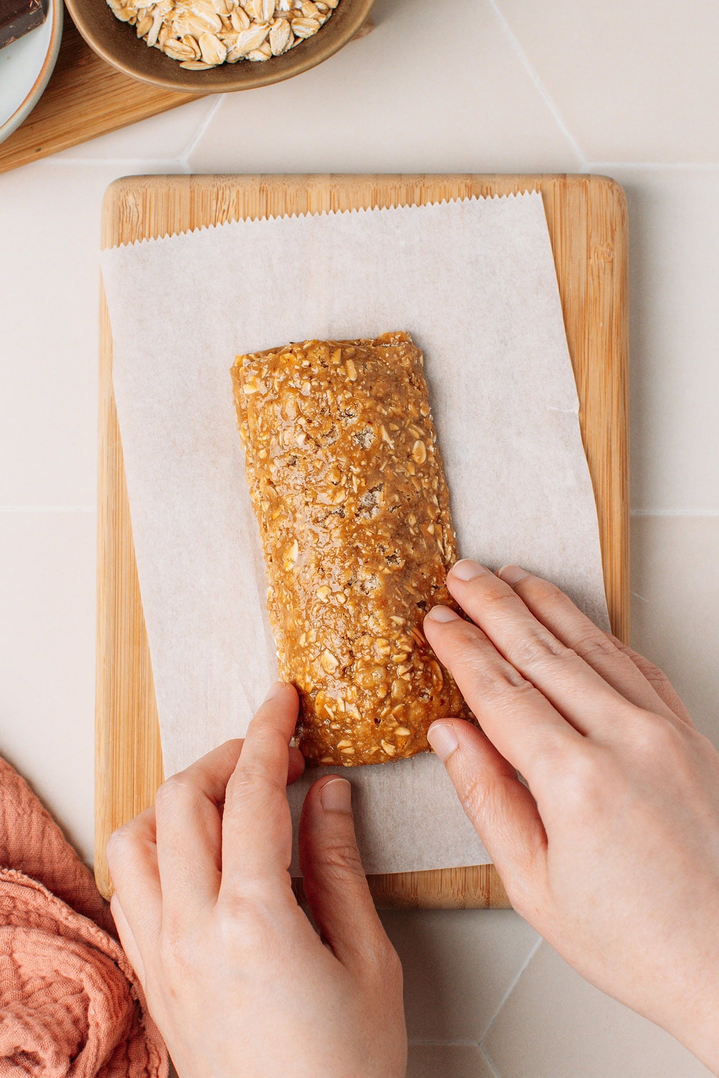 Pressing the edges of a granola bar to enclose the chocolate filling.