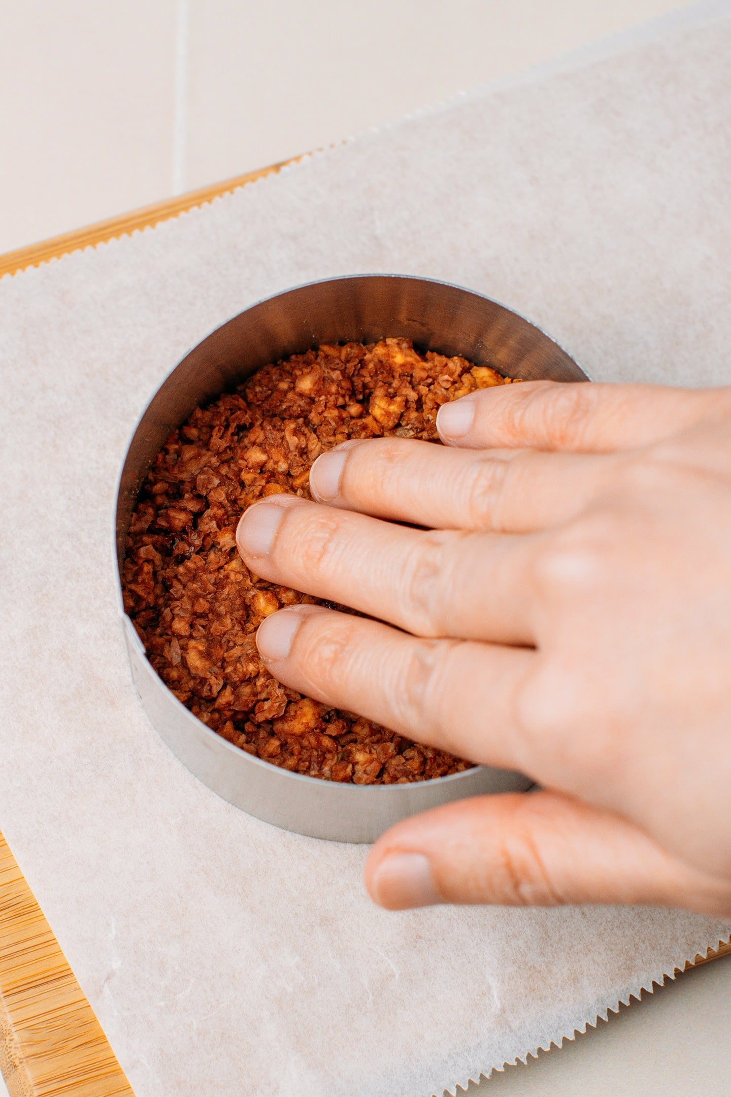 Pressing TVP mixture into a pastry ring to shape it into a patty.