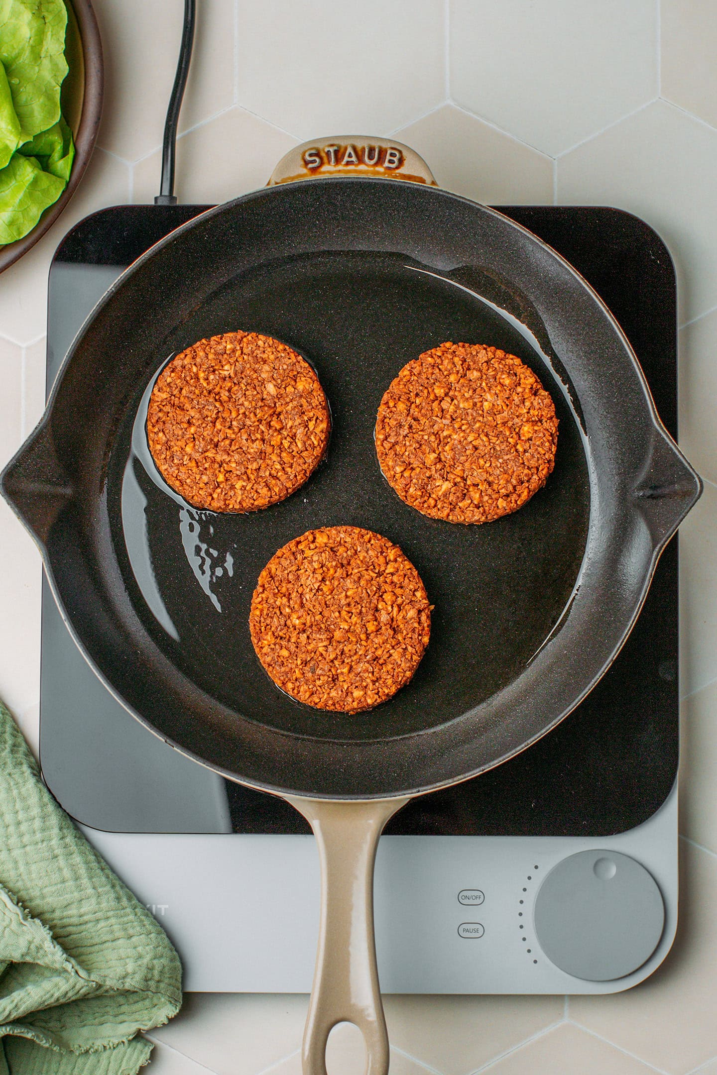 Three vegan patties in a skillet.