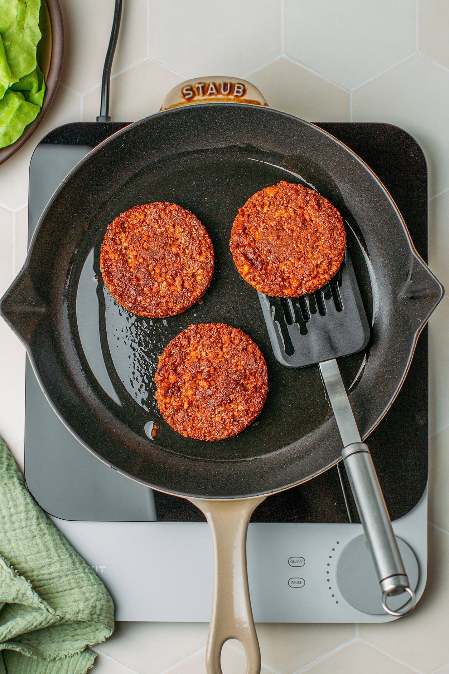 Three cooked vegan burger patties on a skillet.