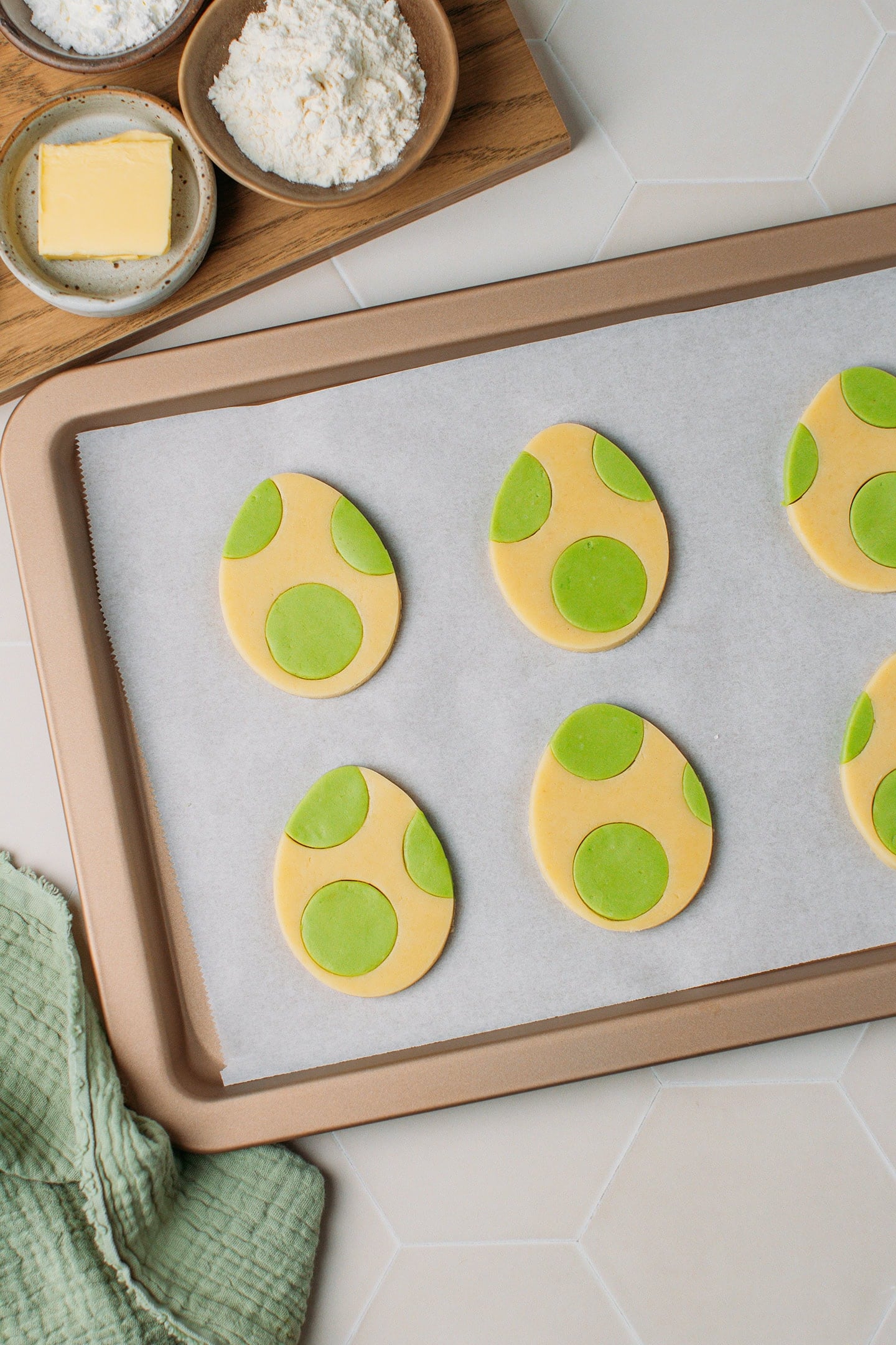 Six egg-shaped cookies on a baking sheet.