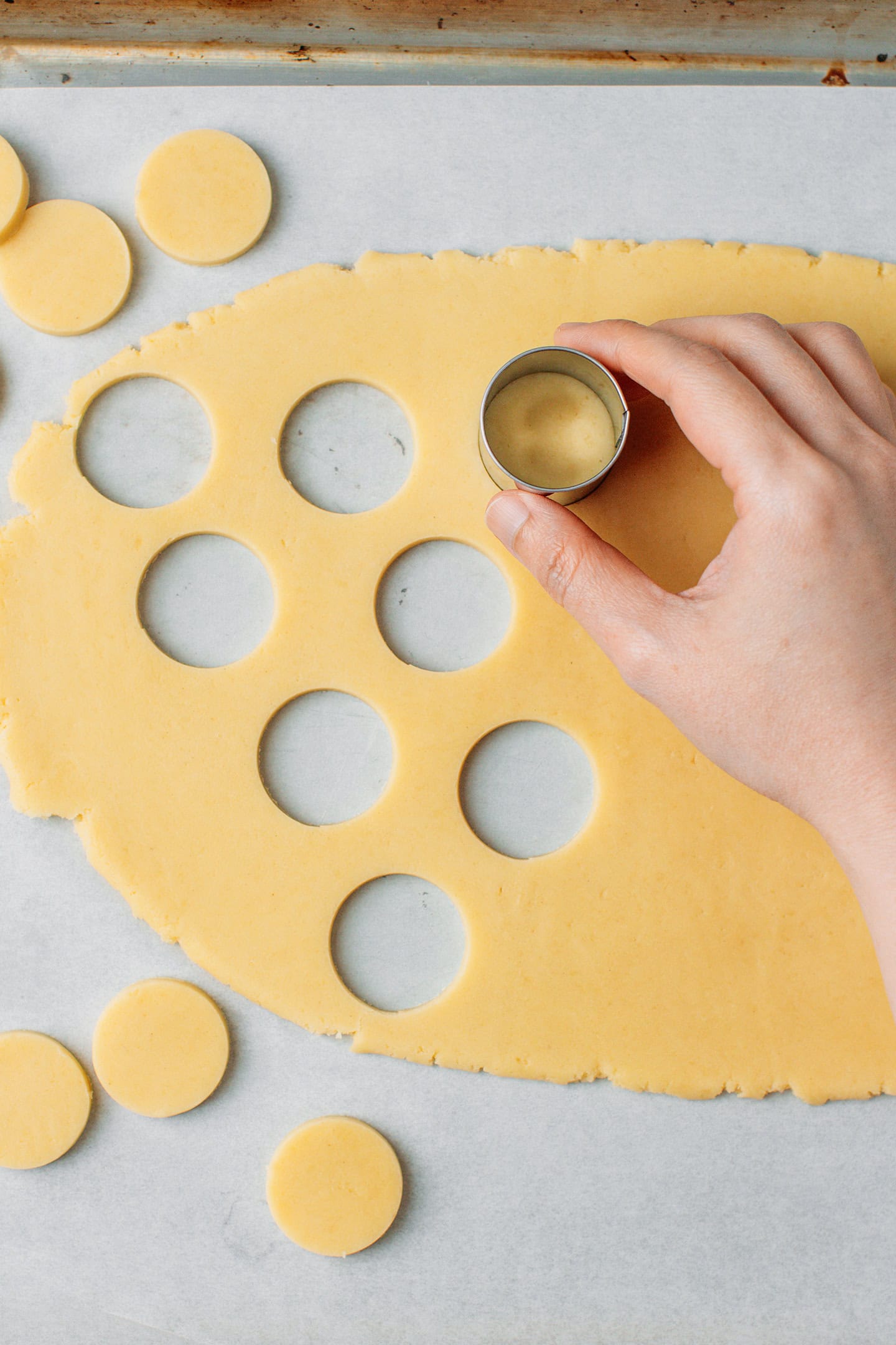 Using a round cookie cutter to cut out dots in a vanilla dough.