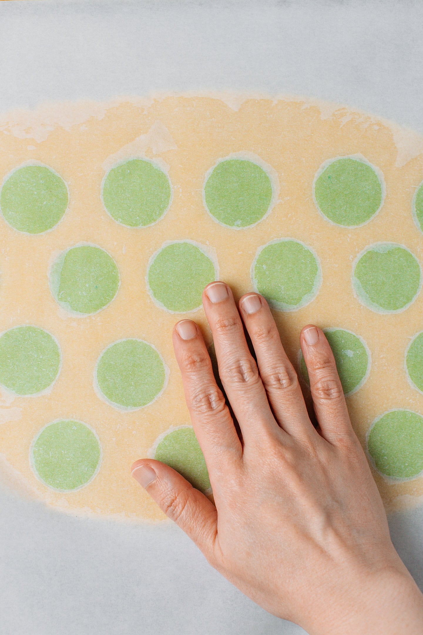 Flattening green-dotted sugar cookie dough.