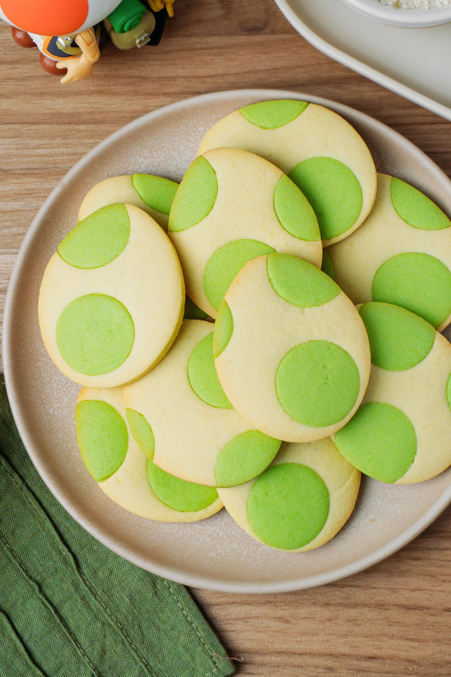 Plate filled with egg-shaped cookies with green dots.