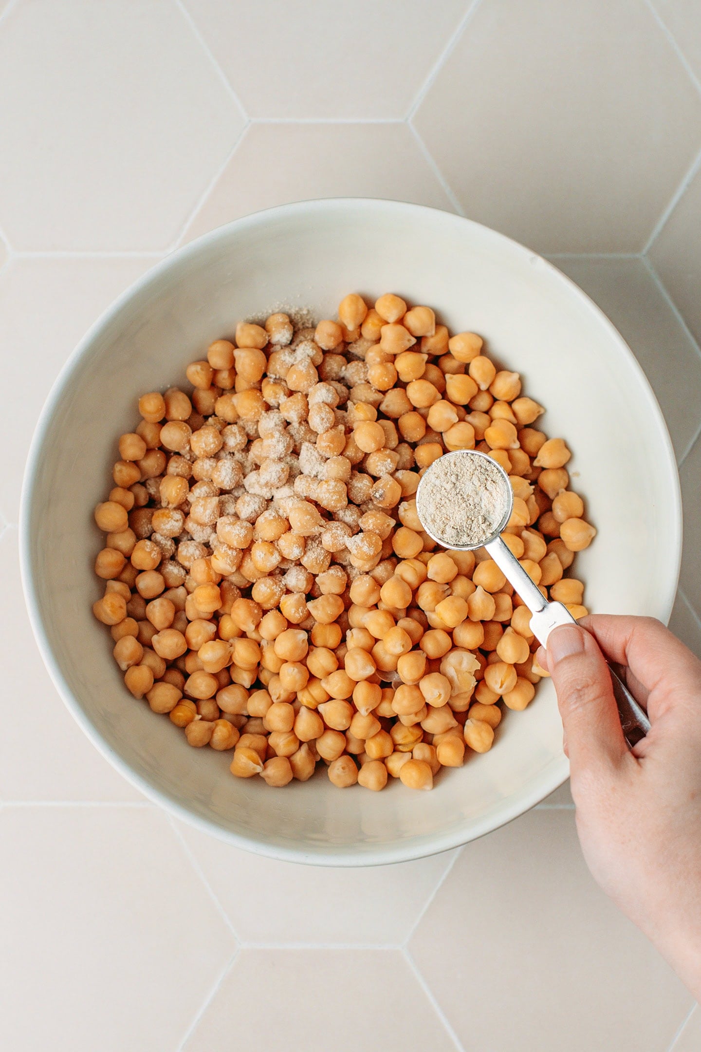 Sprinkling tempeh starter over cooked chickpeas.