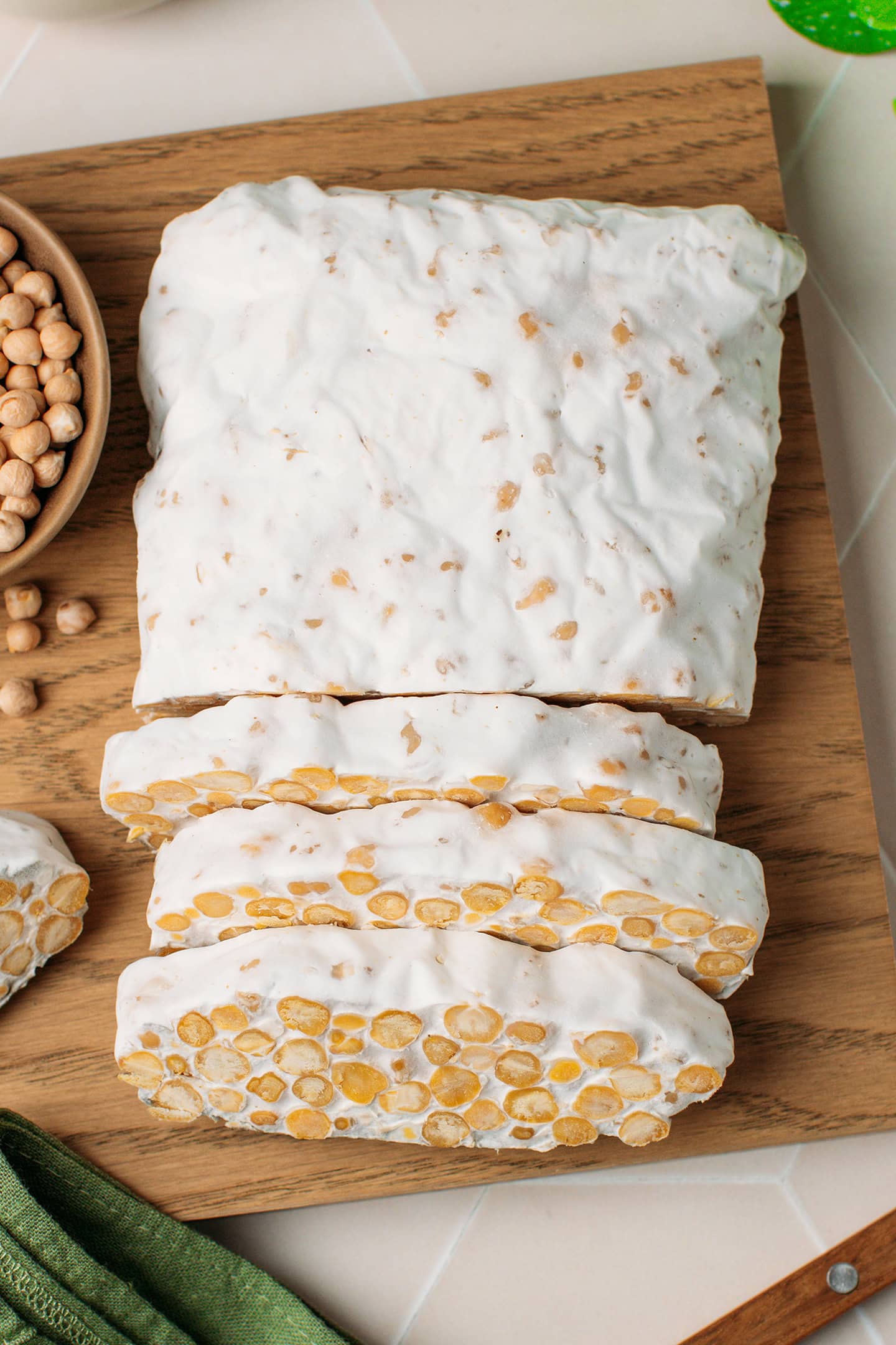 Sliced loaf of chickpea tempeh on a wooden board.