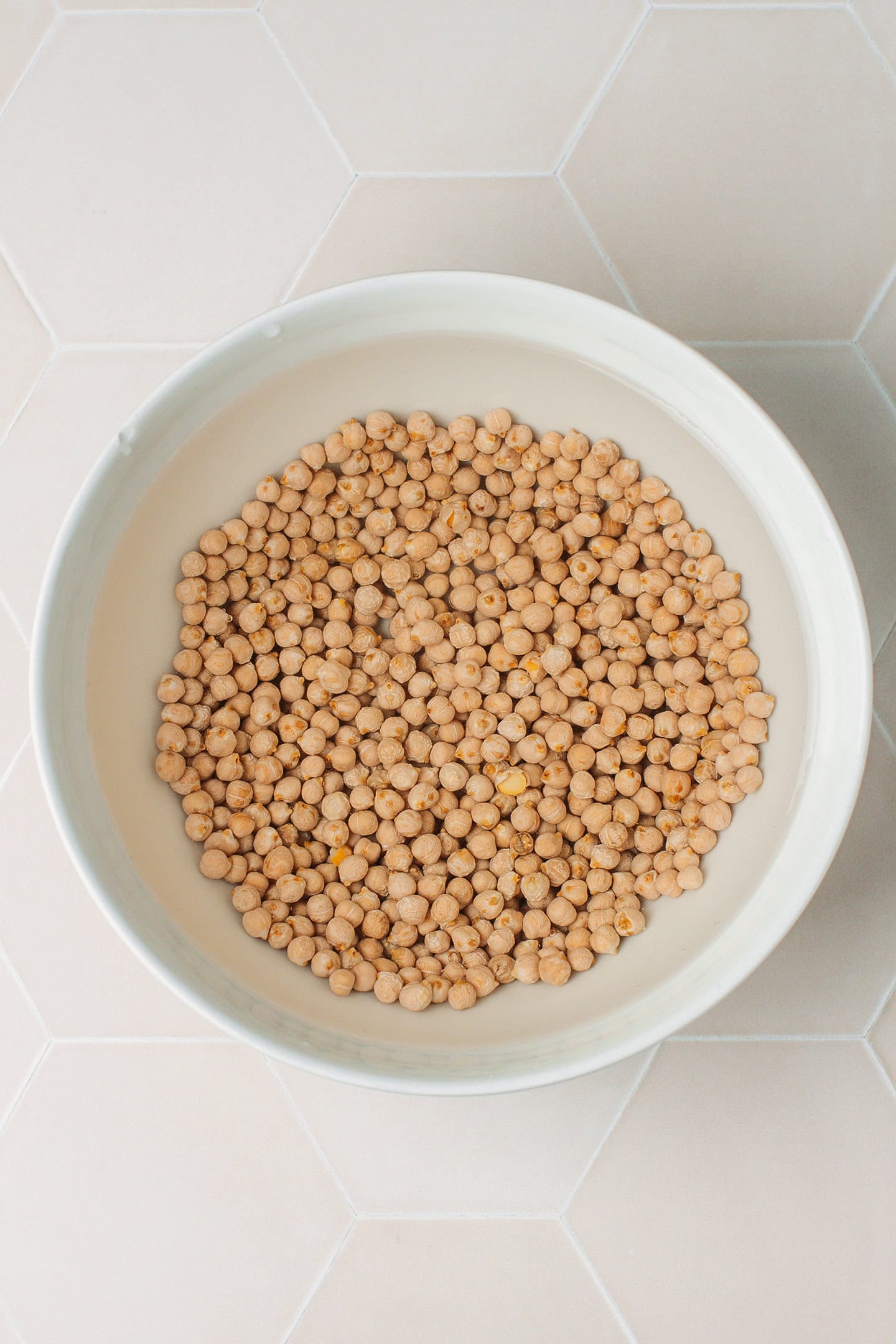 Dry chickpeas soaking in a bowl of water.