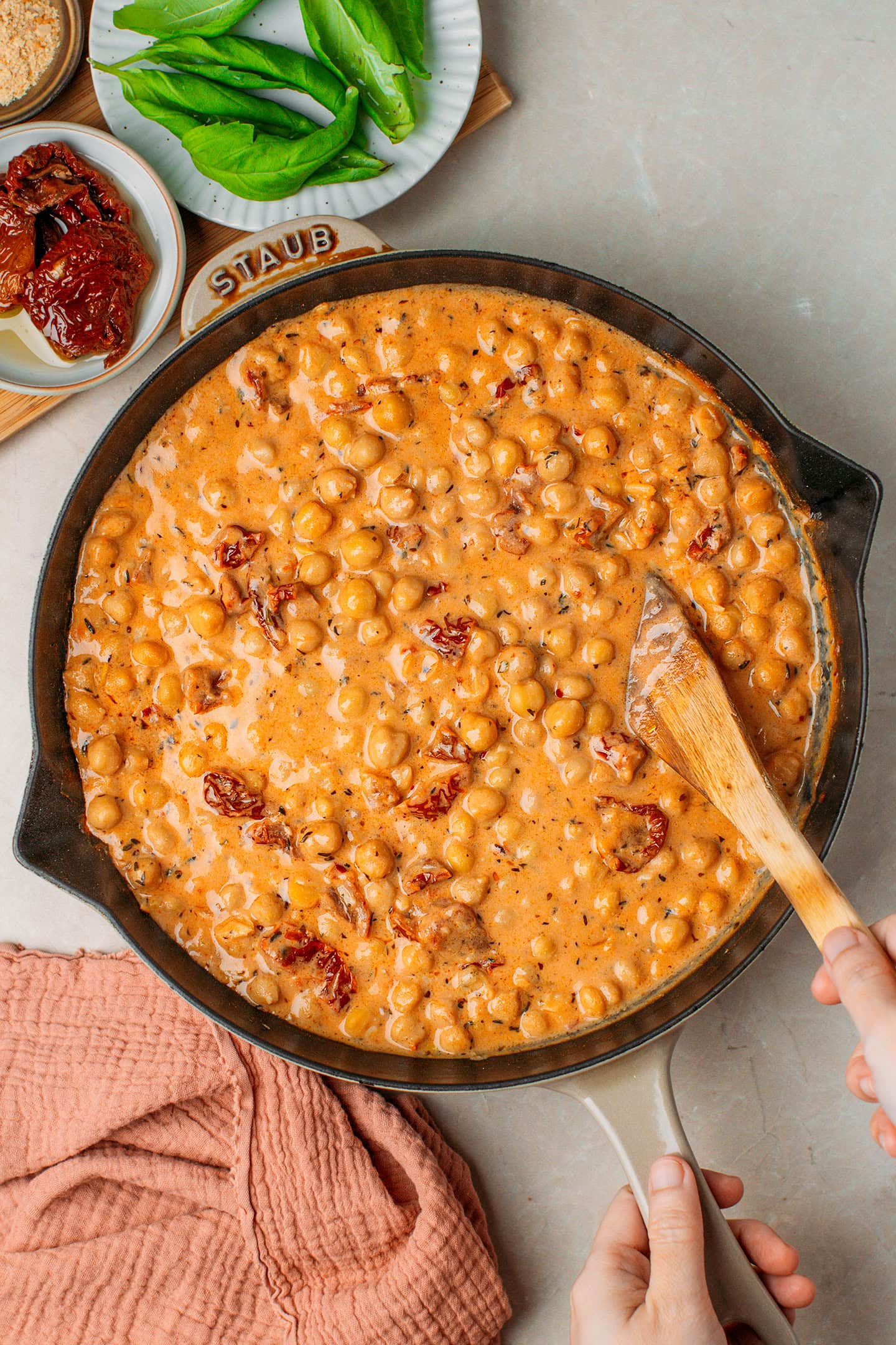 Stirring cooked chickpeas in a creamy Marry Me sauce.
