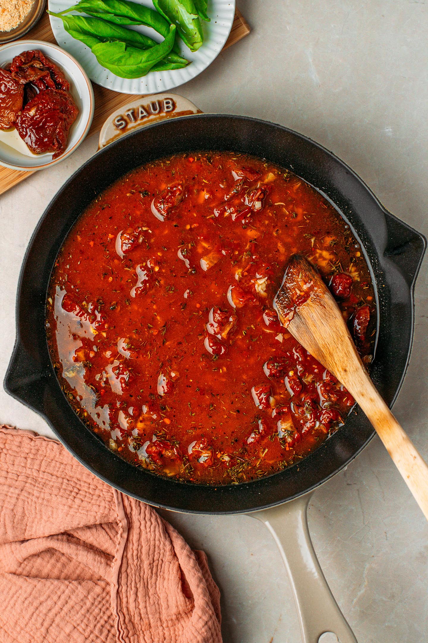 Saut&eacute;ed garlic, sun-dried tomatoes, dried herbs, and vegetable broth in a skillet.