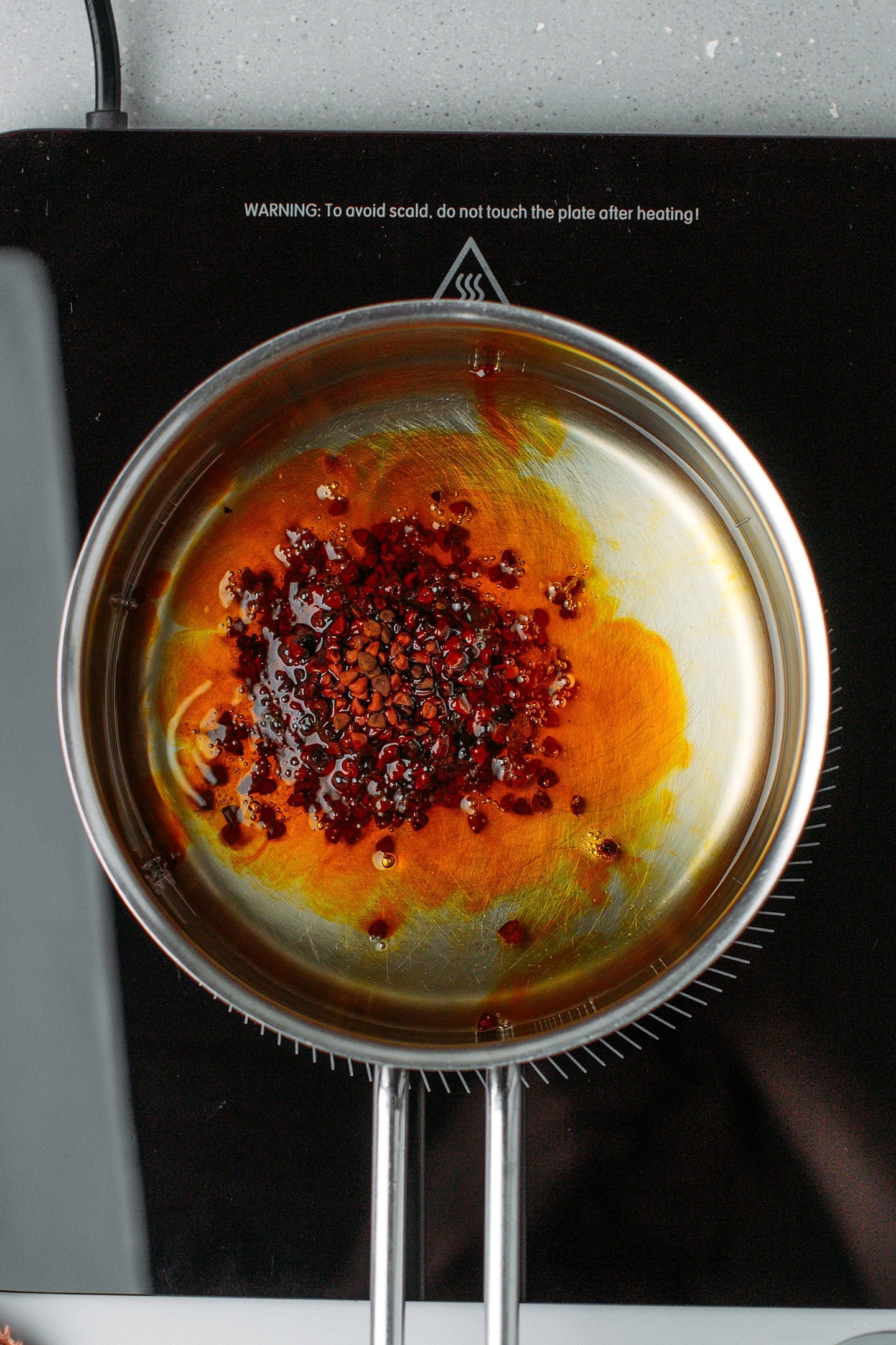 Oil and annatto seeds in a saucepan.