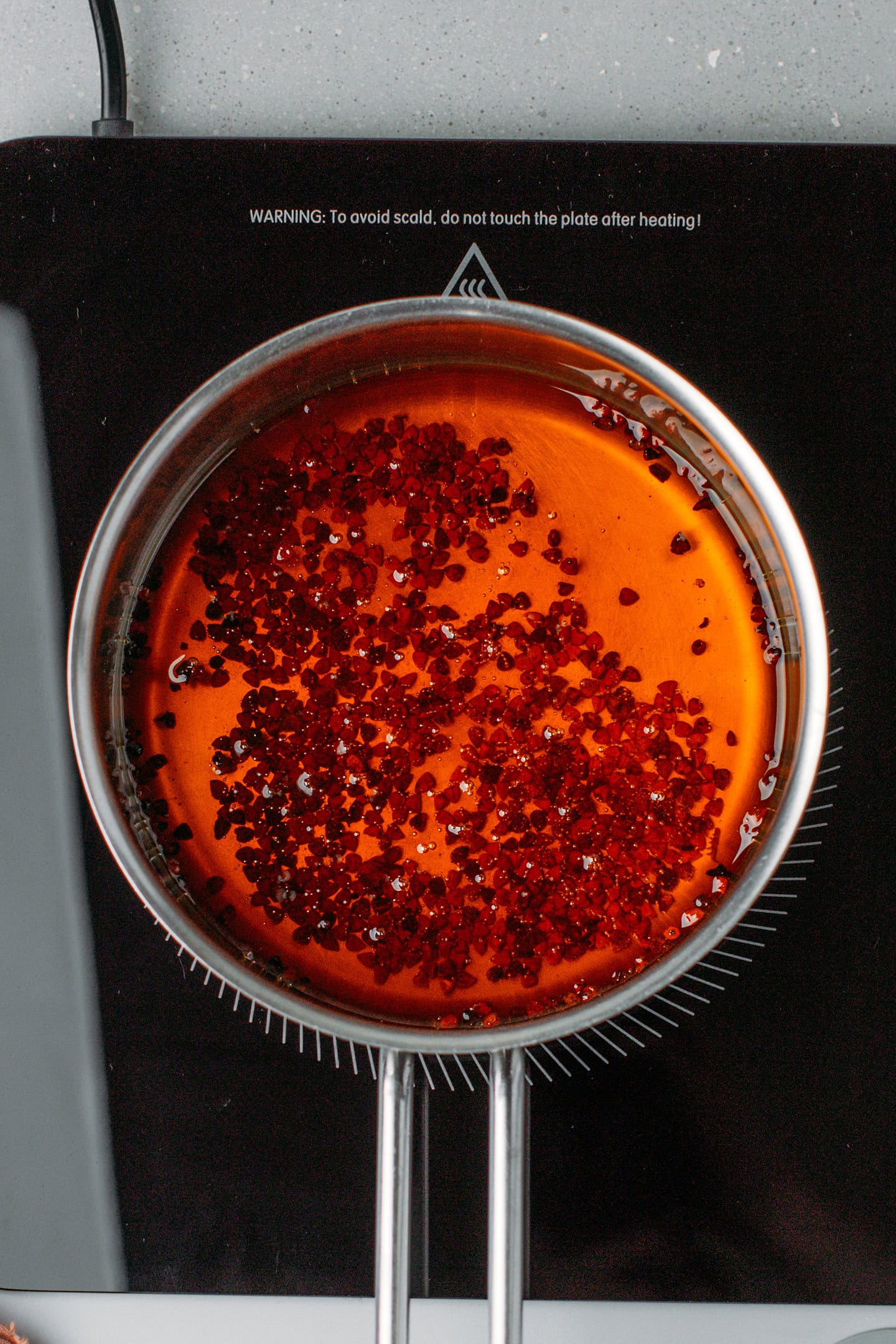 Red oil and annatto seeds in a saucepan.