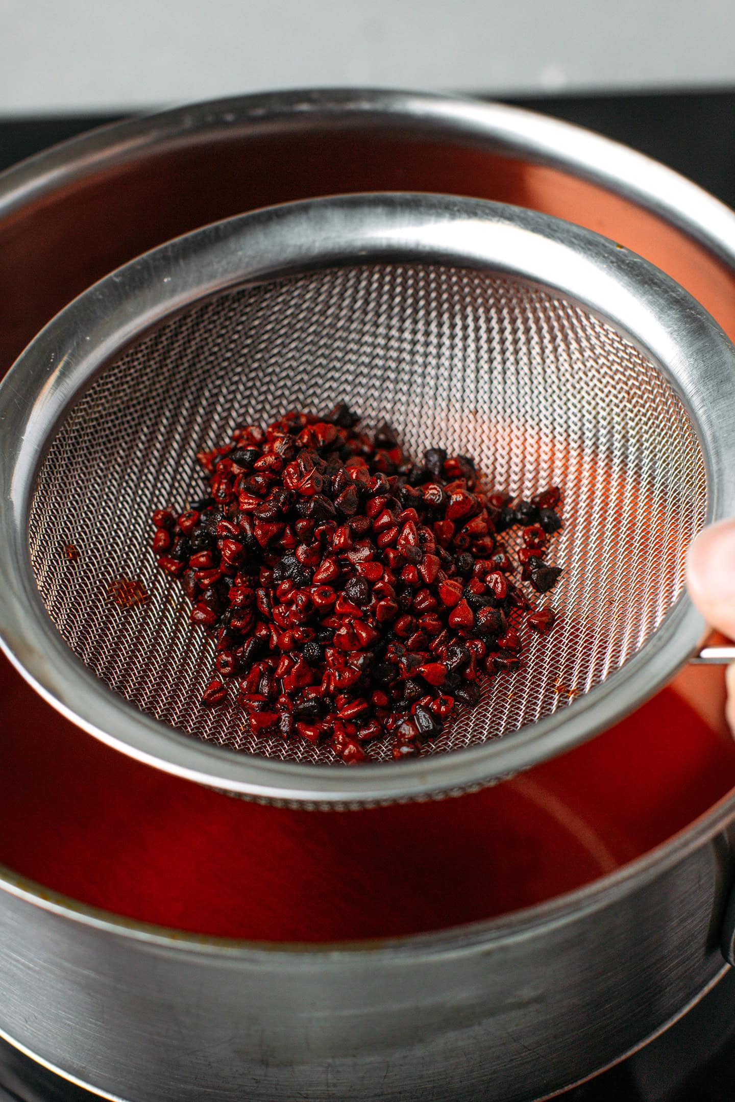 Straining the oil using a fine mesh sieve.