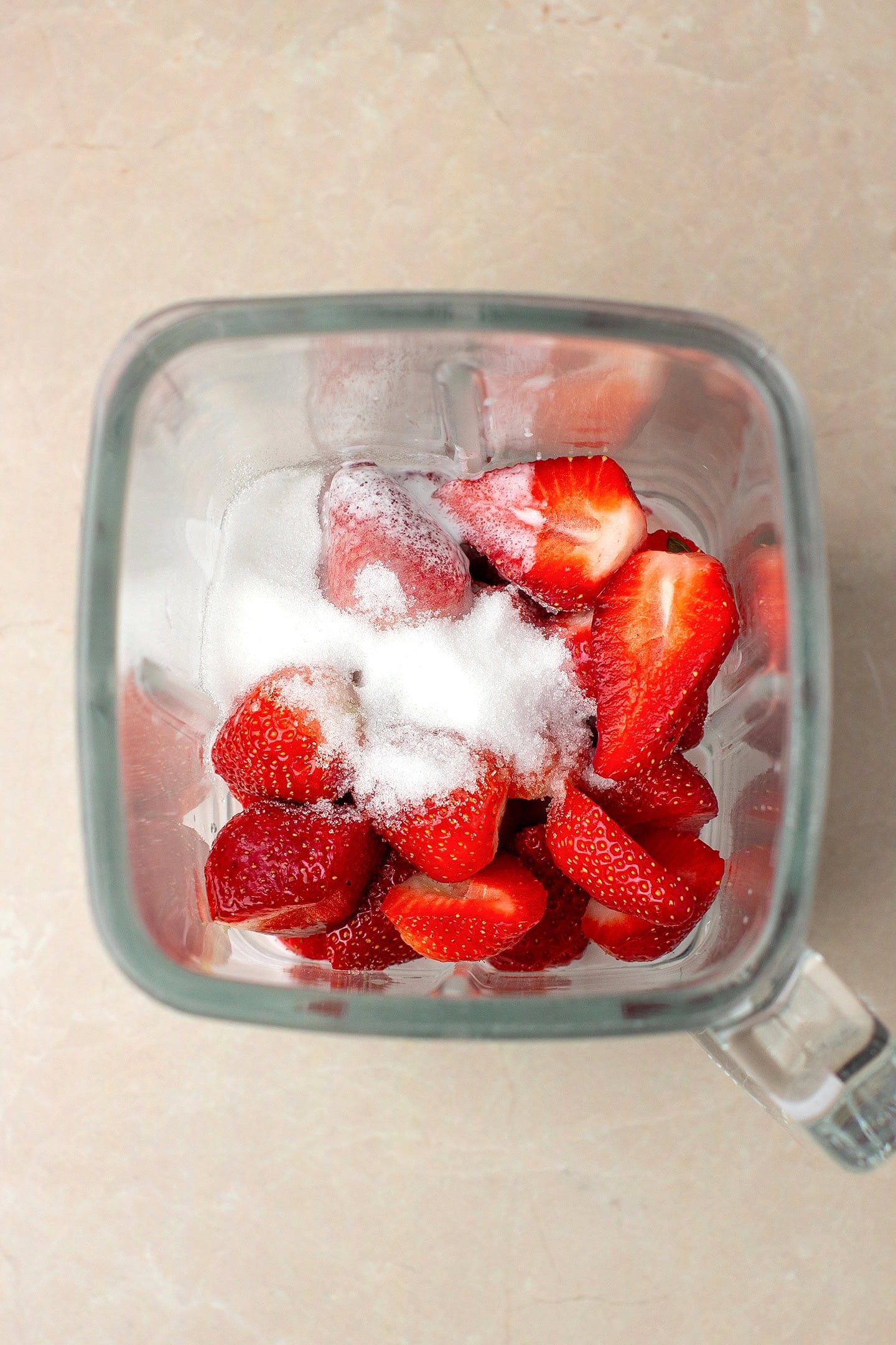 Fresh strawberries, coconut milk, and sugar in a blender.
