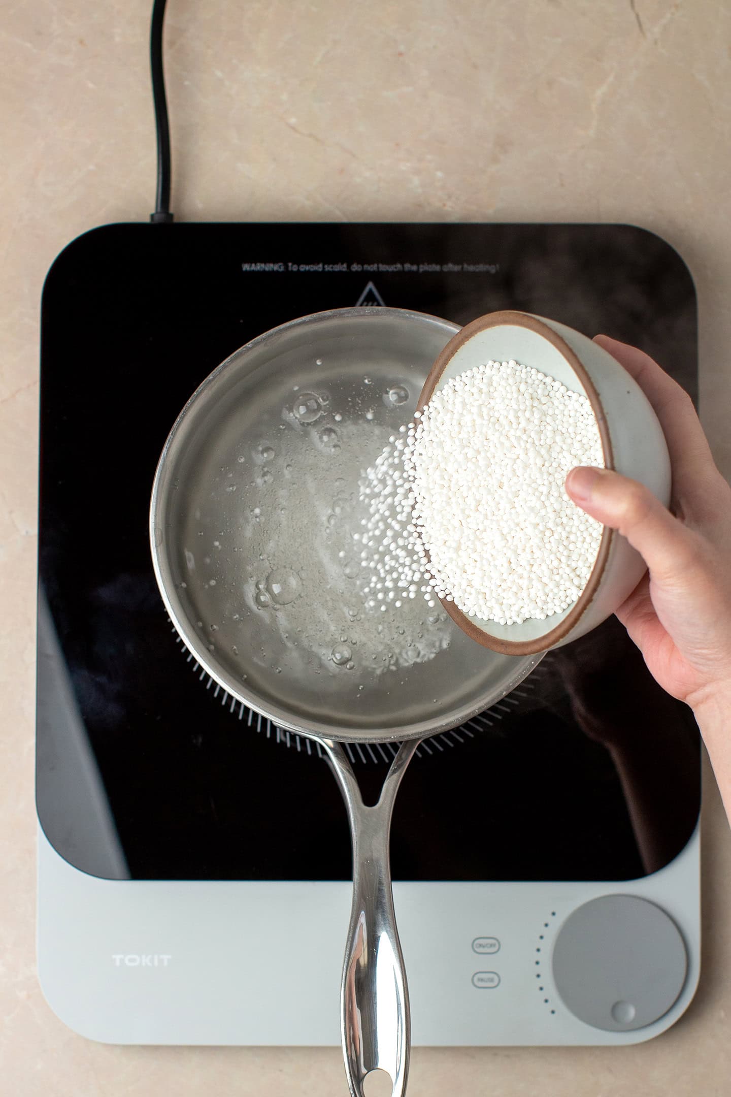 Adding tapioca pearls to a pot of boiling water.