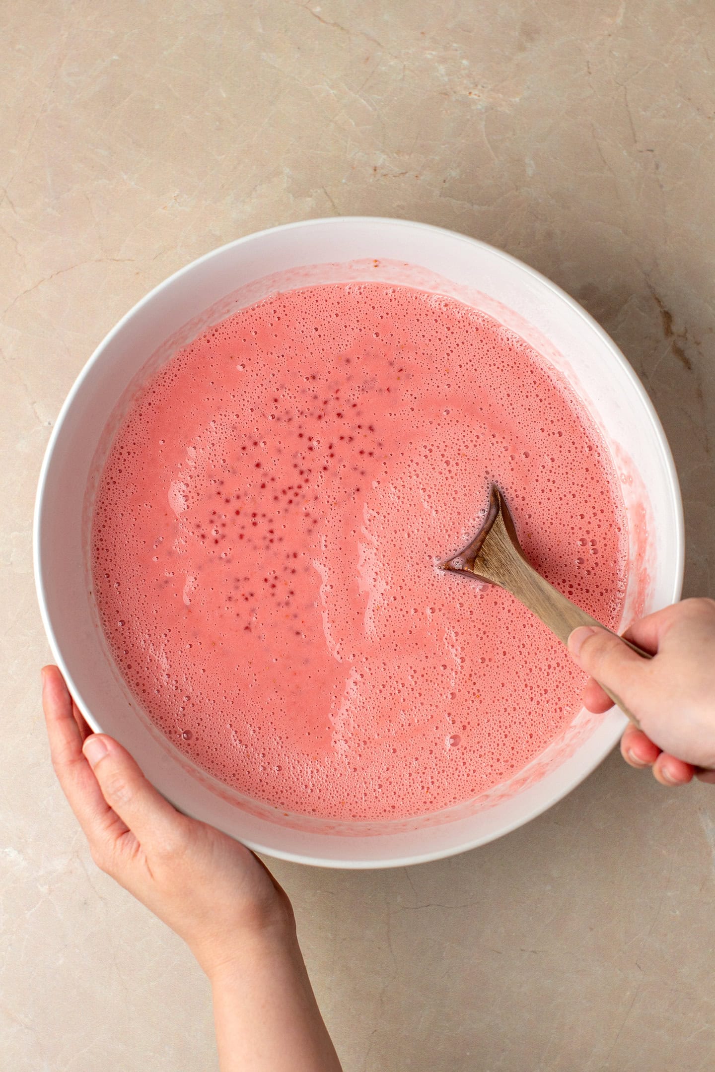 Mixing tapioca pearls with blended strawberries.