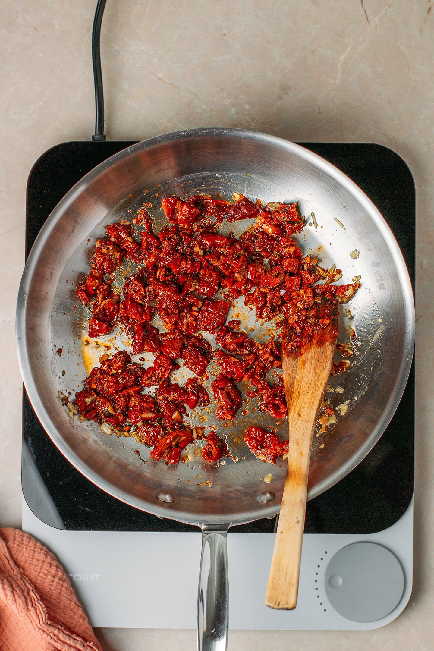 Saut&eacute;ed chopped sun-dried tomatoes in a skillet.