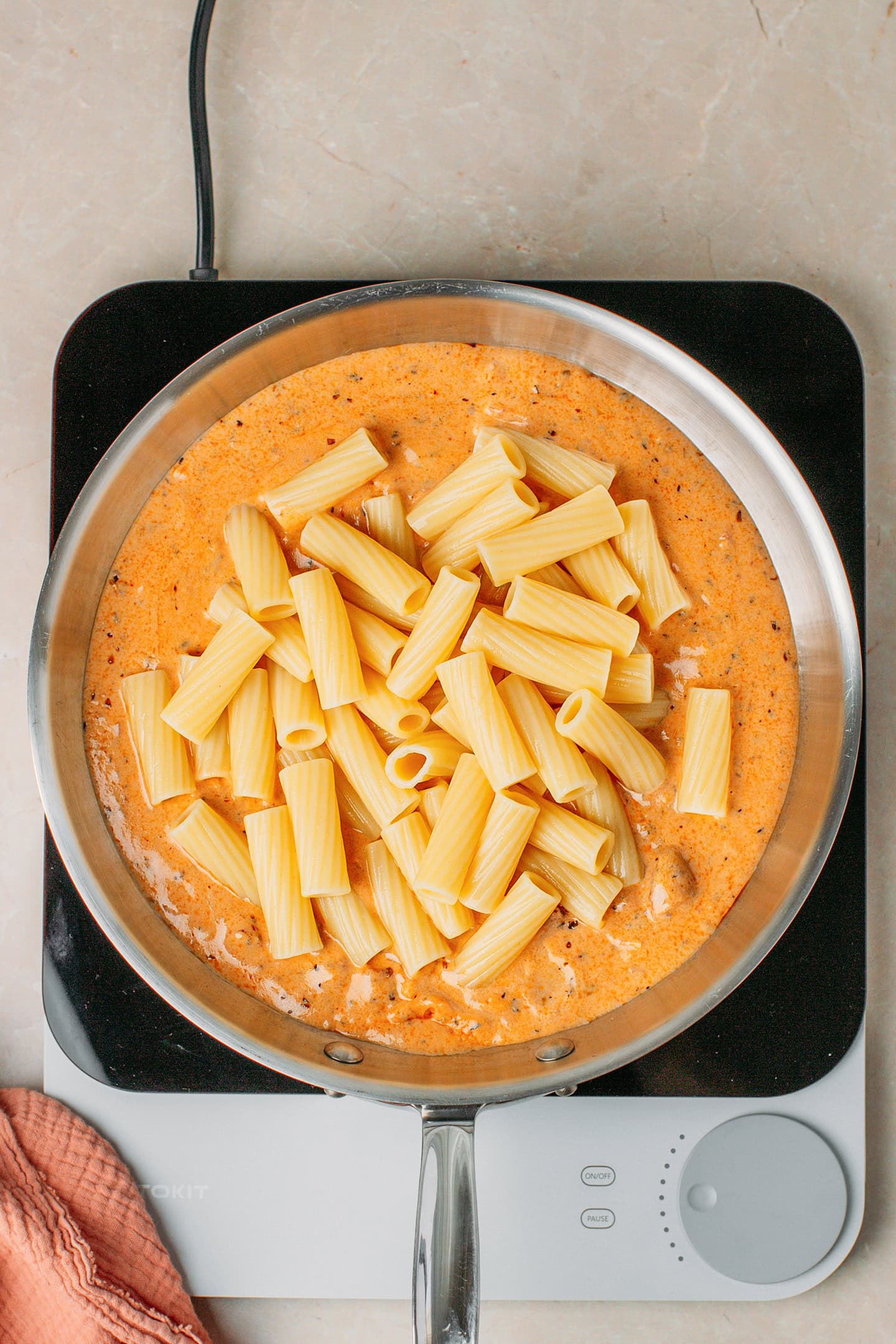 Sun-dried tomato sauce and pasta in a skillet.