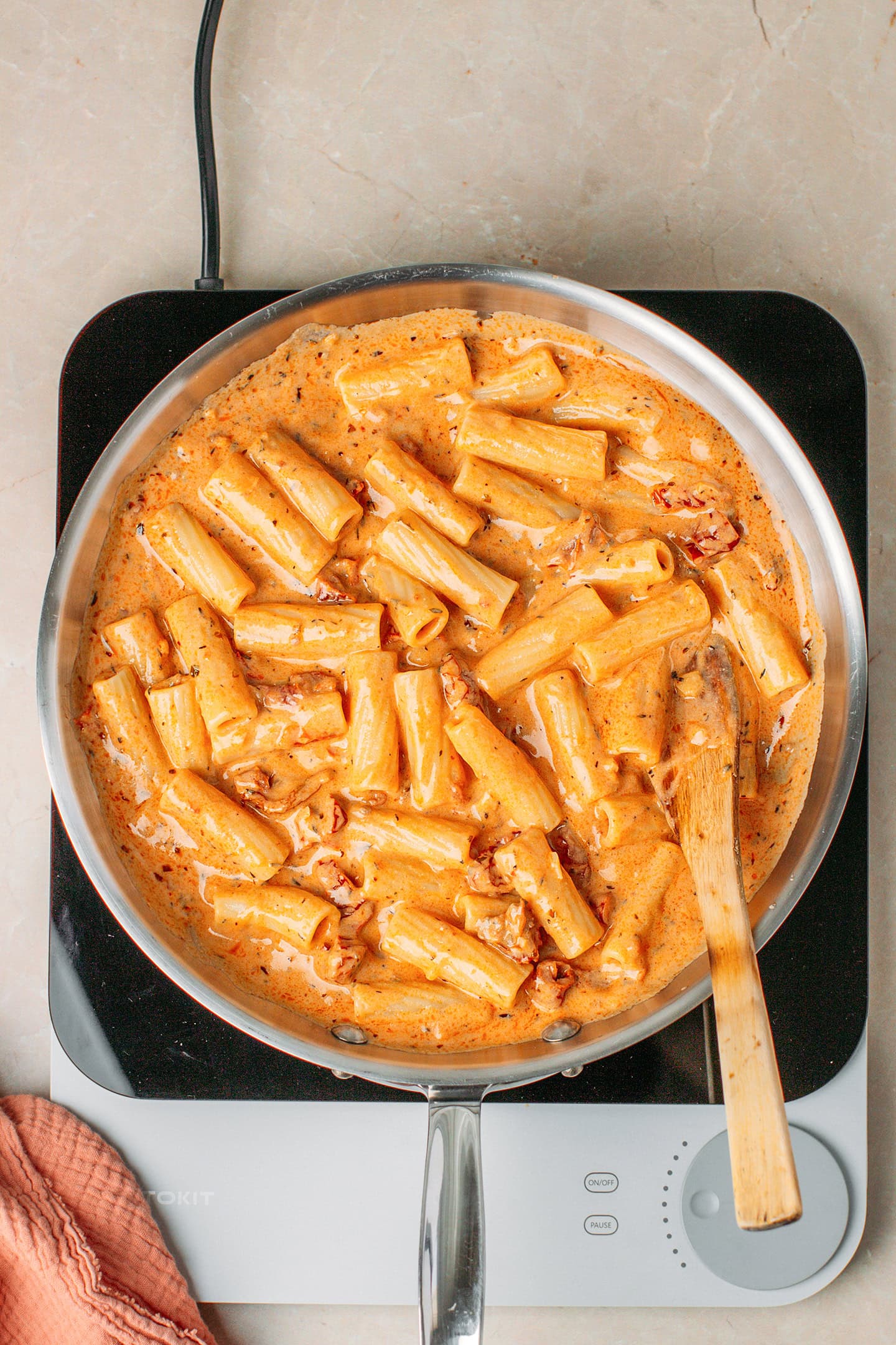 Pasta tossed in a sun-dried tomato sauce in a skillet.