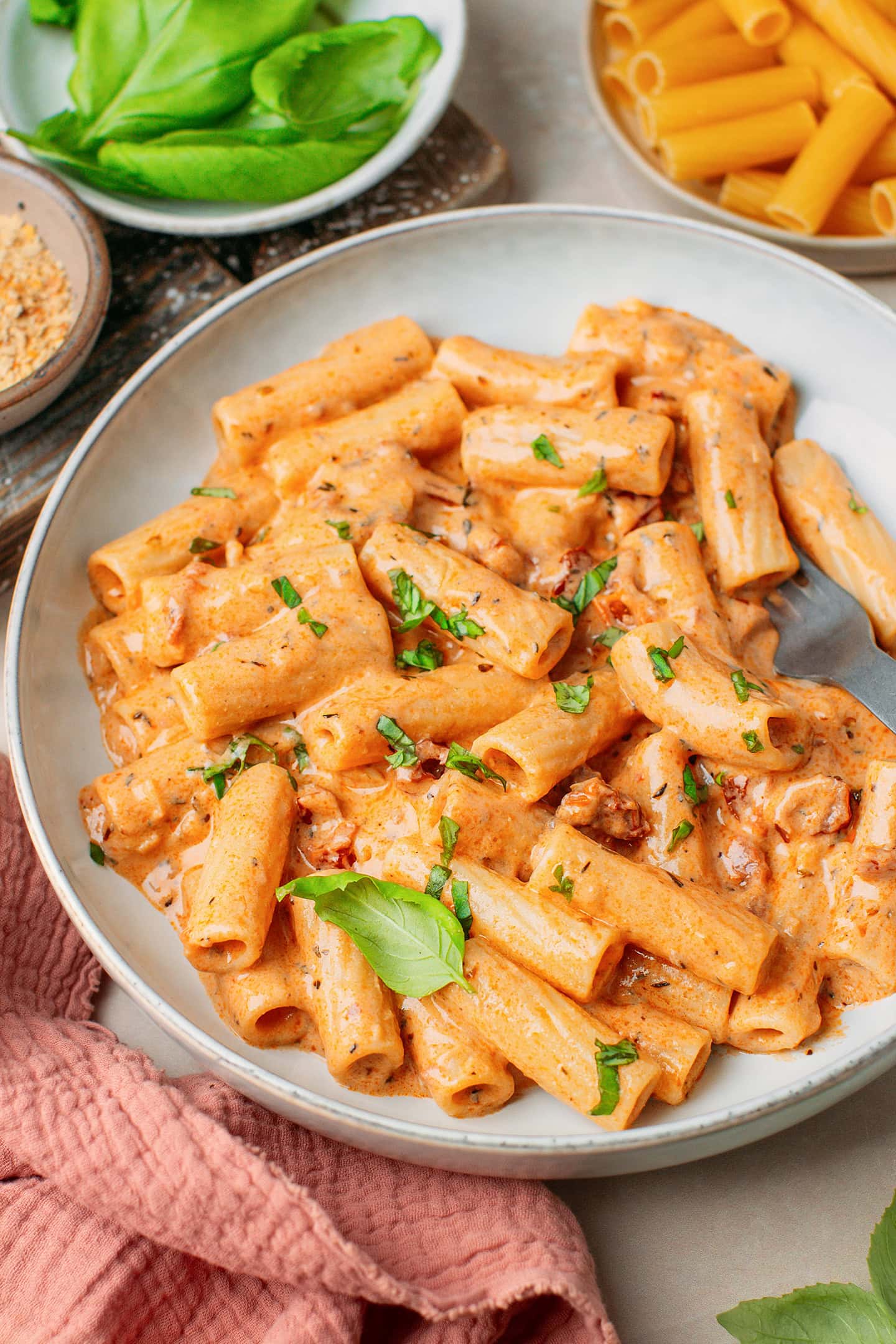 Pasta tossed with a sun-dried tomato sauce and topped with chopped basil in a plate.