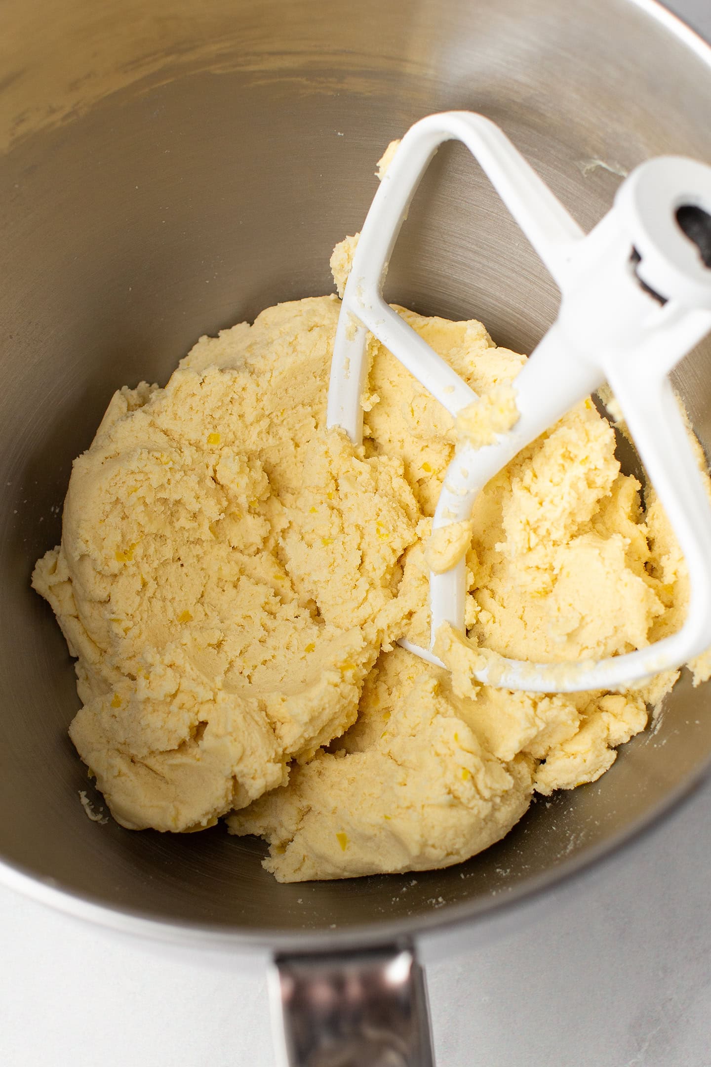 Lemon cookie dough in the bowl of a stand mixer.