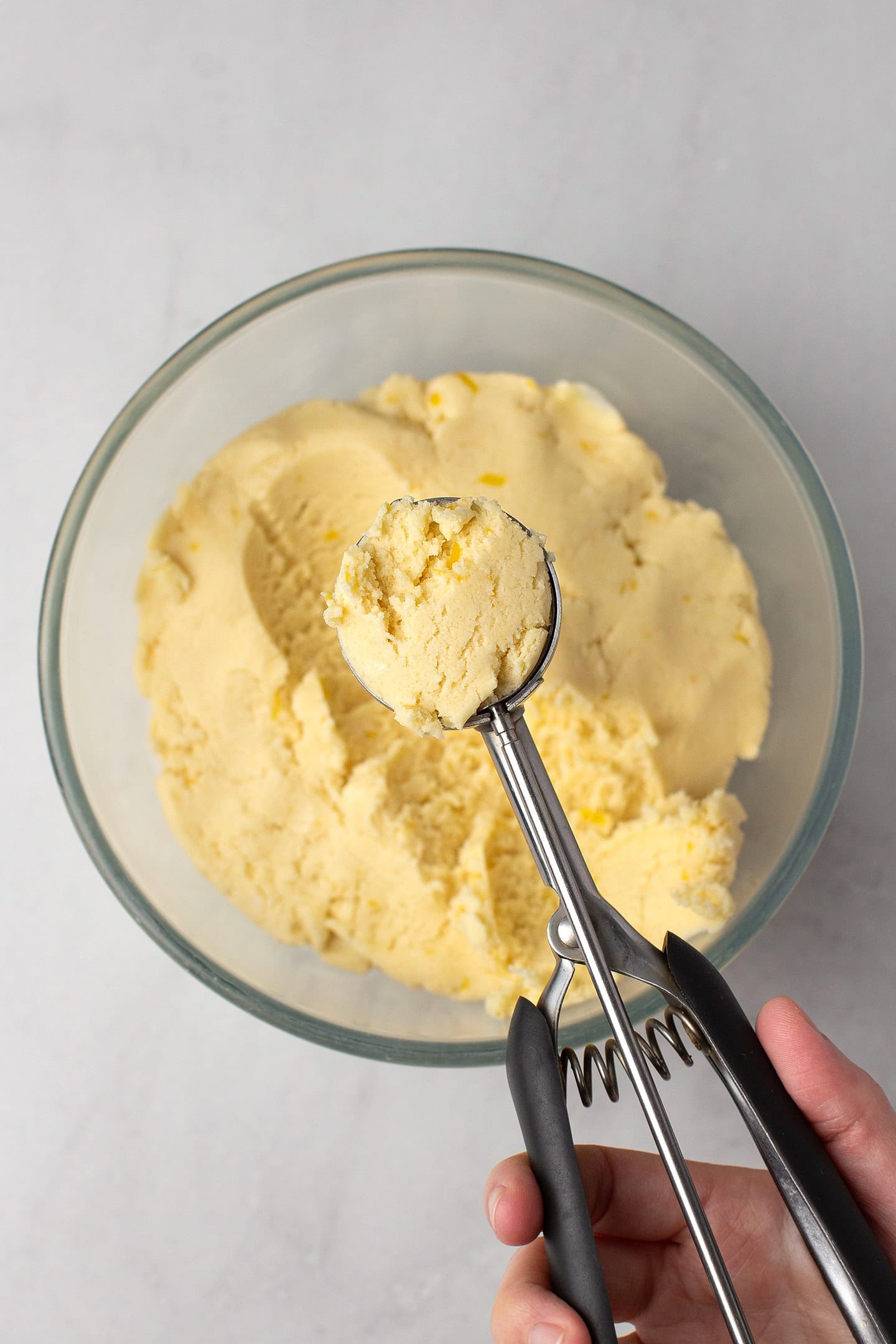 Using a cookie scoop to portion lemon cookie dough.