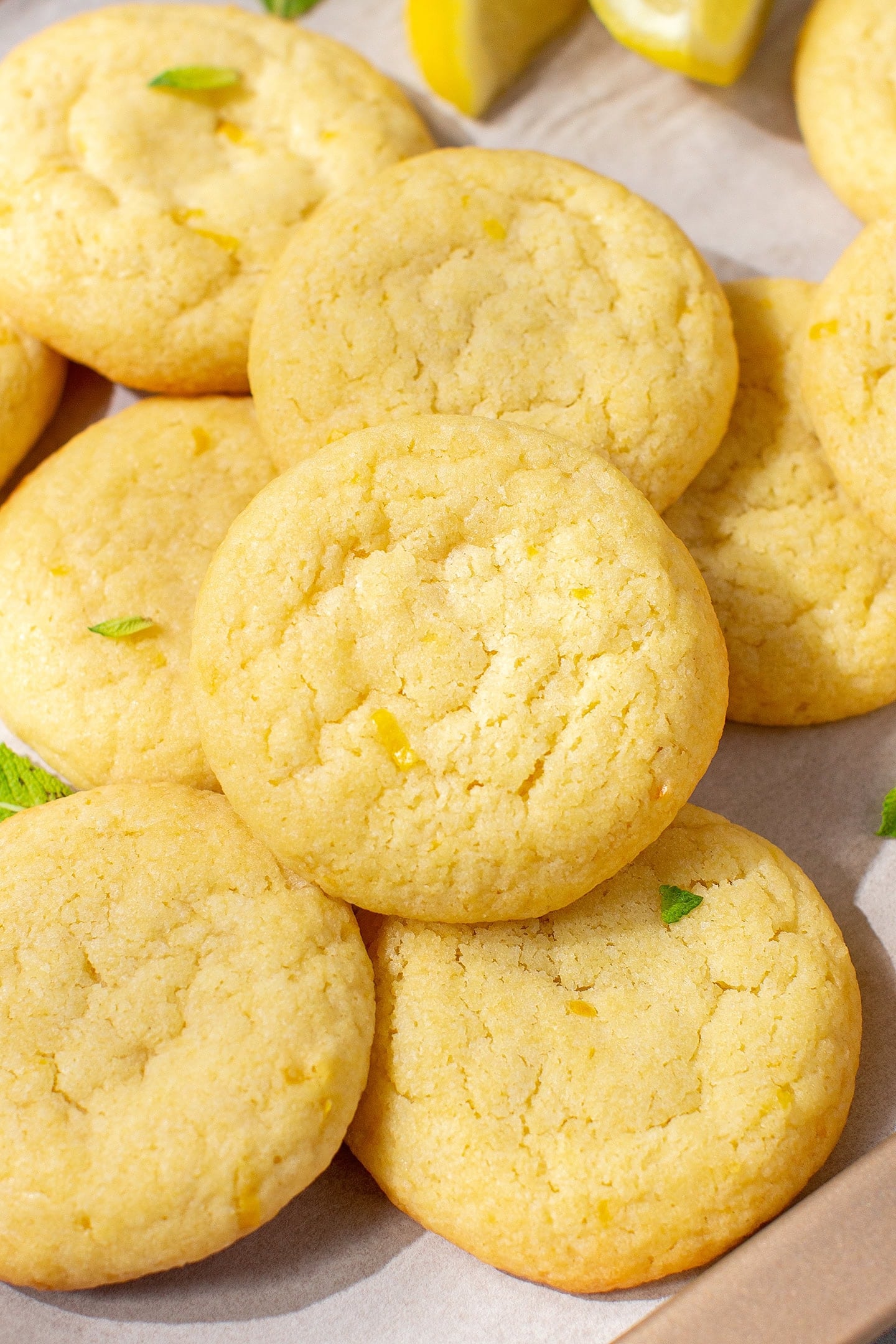 Stacked lemon cookies with mint leaves on a baking sheet.