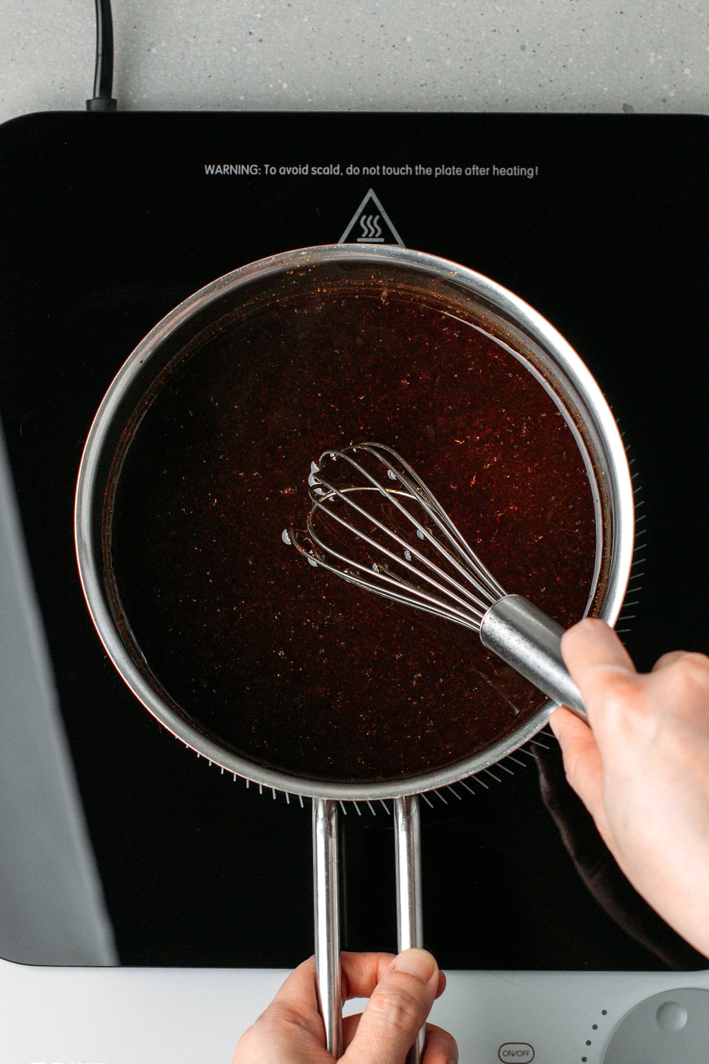 Whisking vegan Worcestershire sauce in a saucepan.