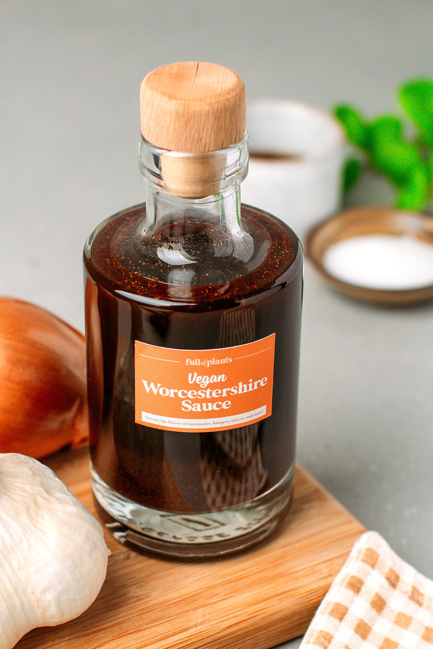 Glass bottle filled with homemade Worcestershire sauce on a wooden board.