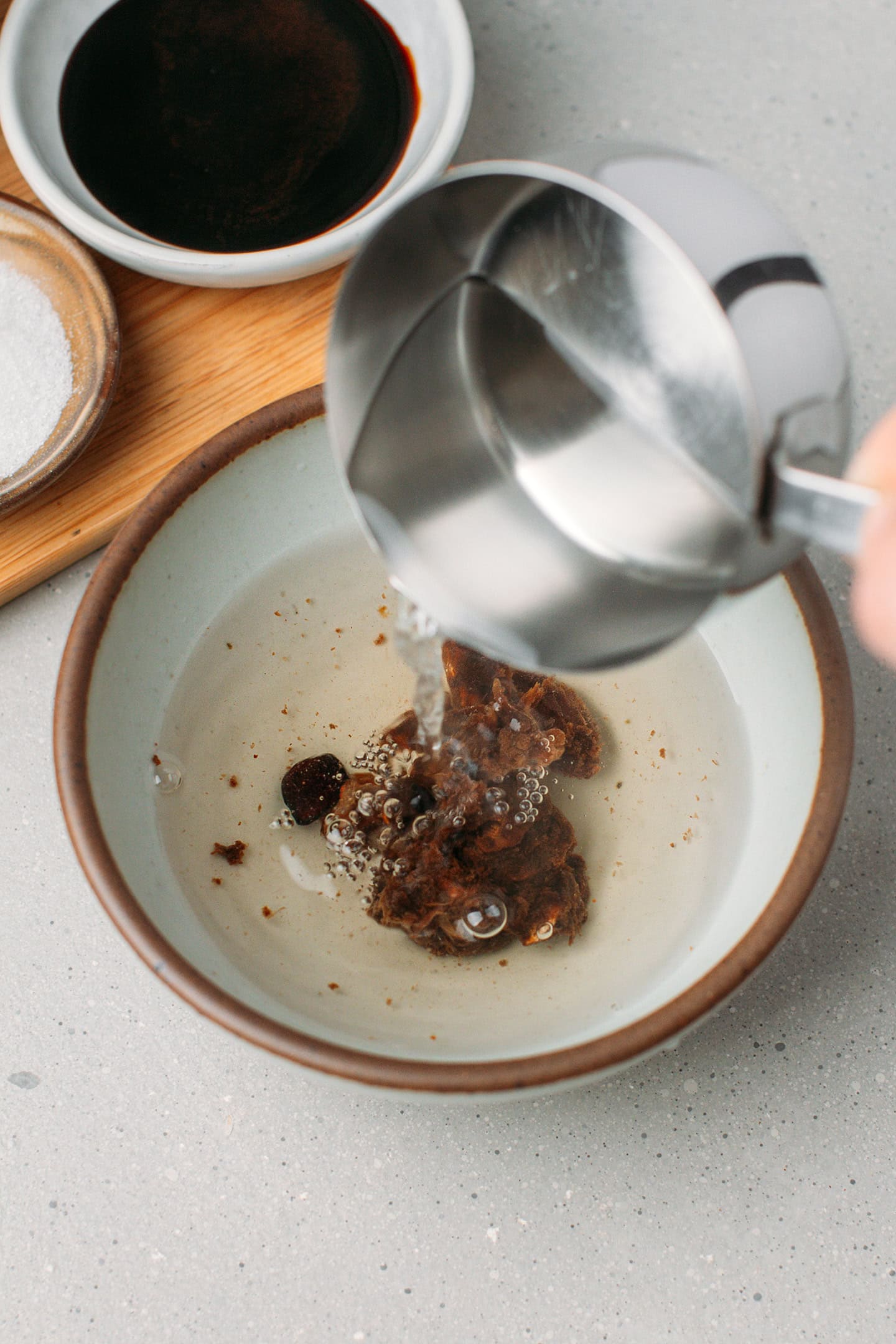 Pouring hot water over tamarind pulp in a bowl.