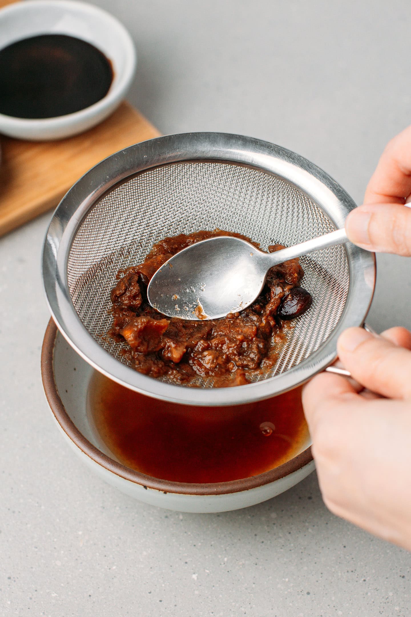 Straining tamarind pulp through a fine-mesh sieve.