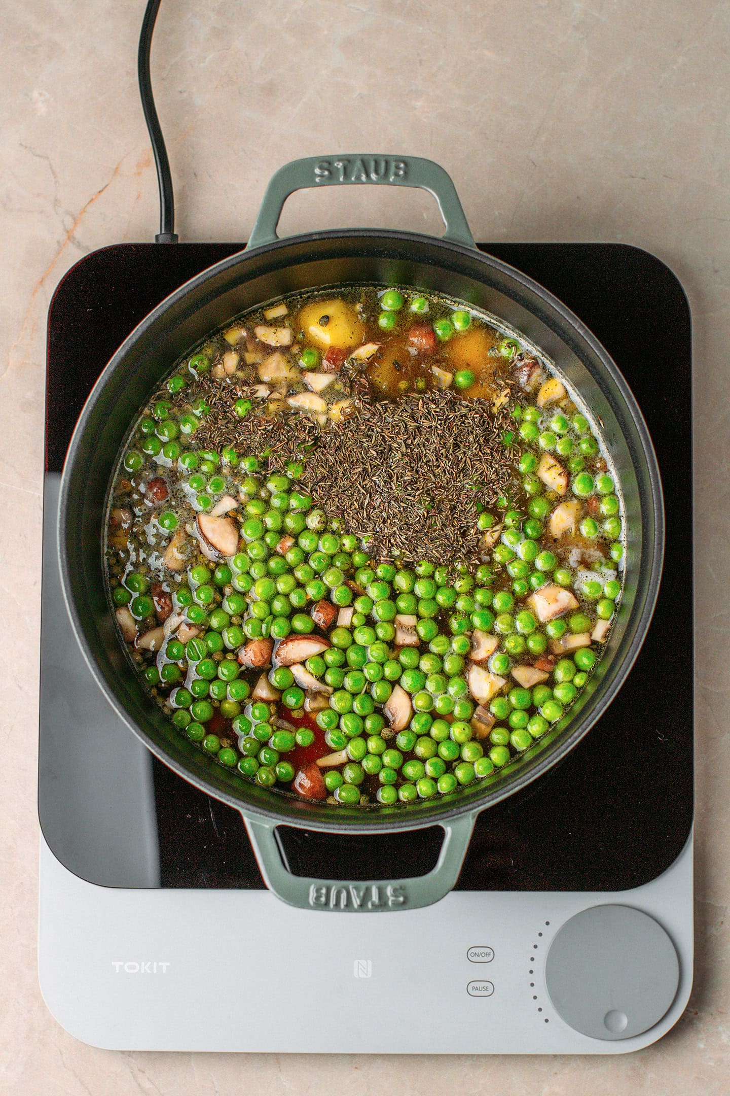Green peas, mushrooms, potatoes, and vegetable broth in a pot.