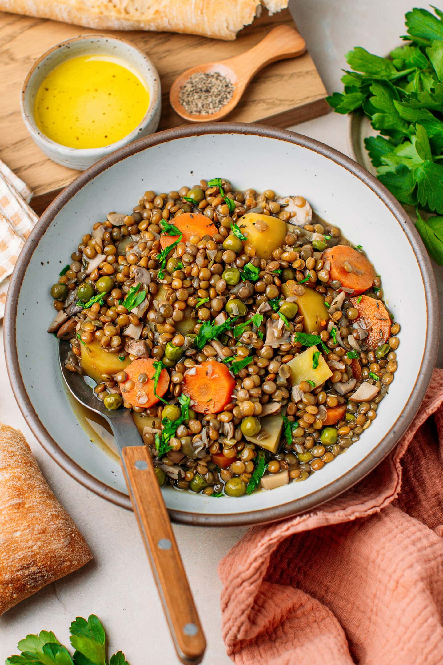 Deep plate filled with lentil stew, diced potatoes, carrots, and chopped parsley.