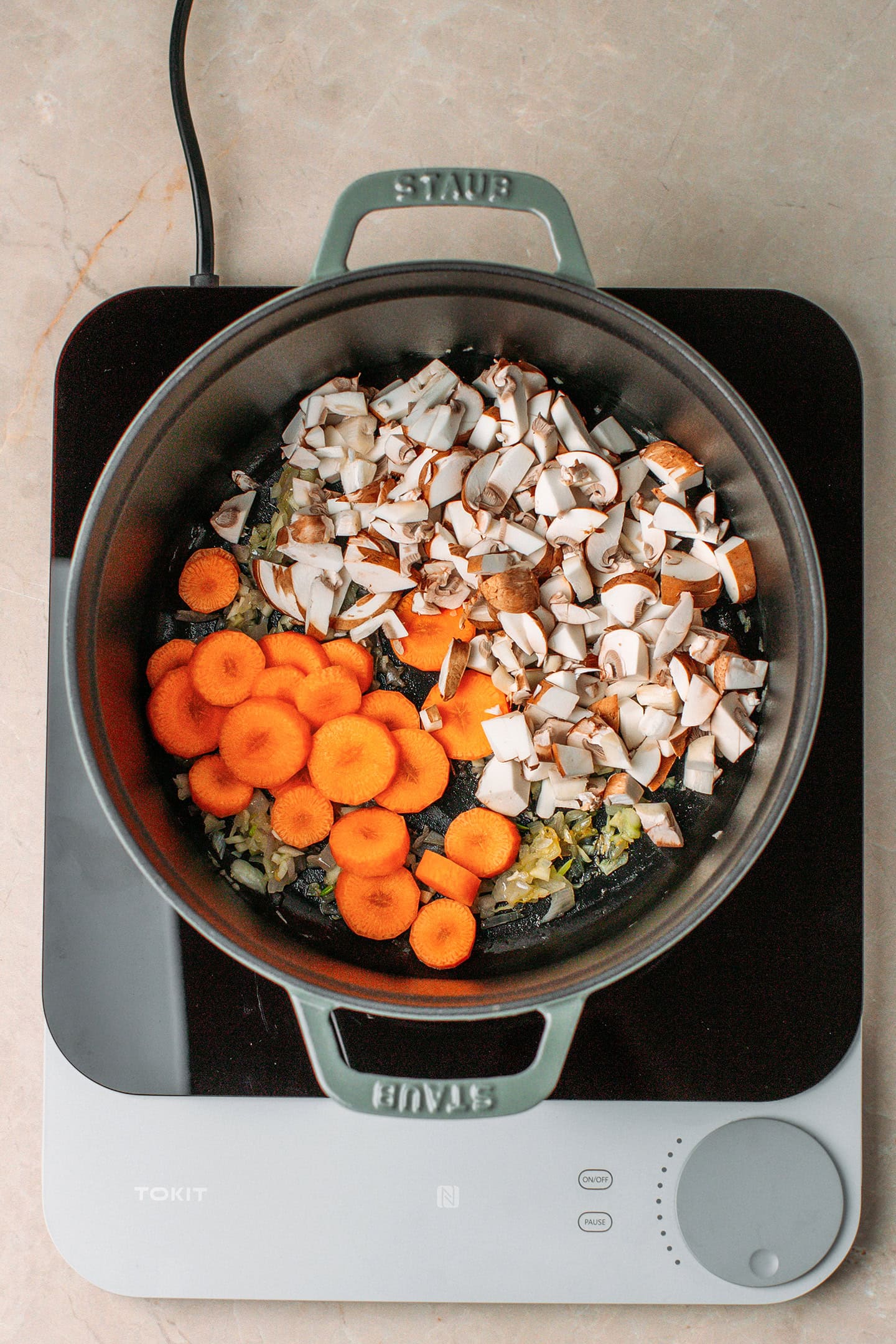 Sliced carrots and diced mushrooms in a pot.