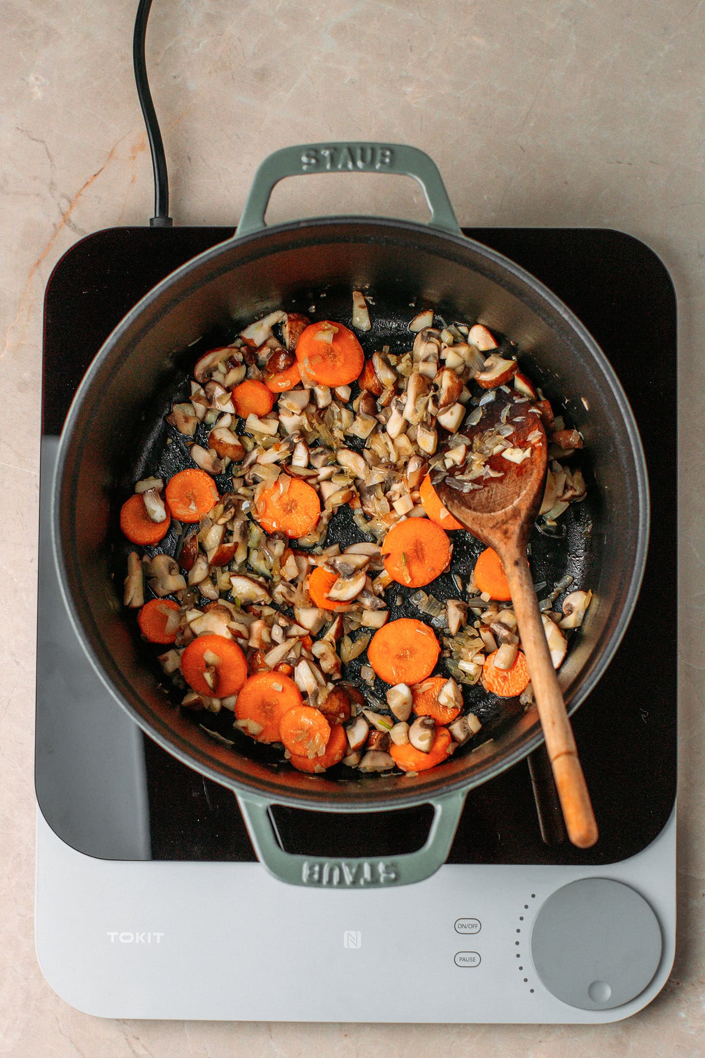 Sautéed mushrooms and carrots in a pot.