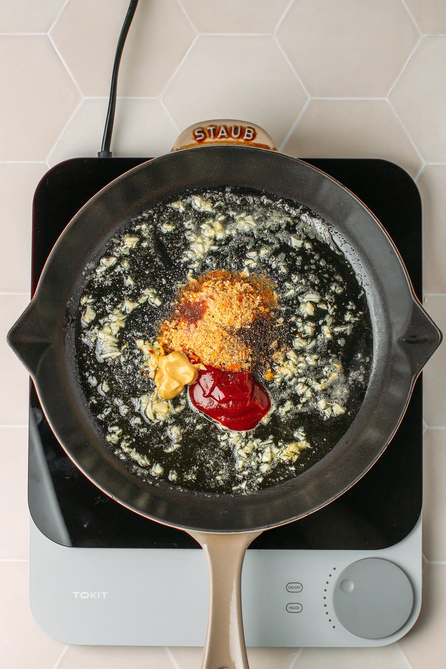 Saut&eacute;ed garlic, nutritional yeast, ketchup, and mustard in a skillet.