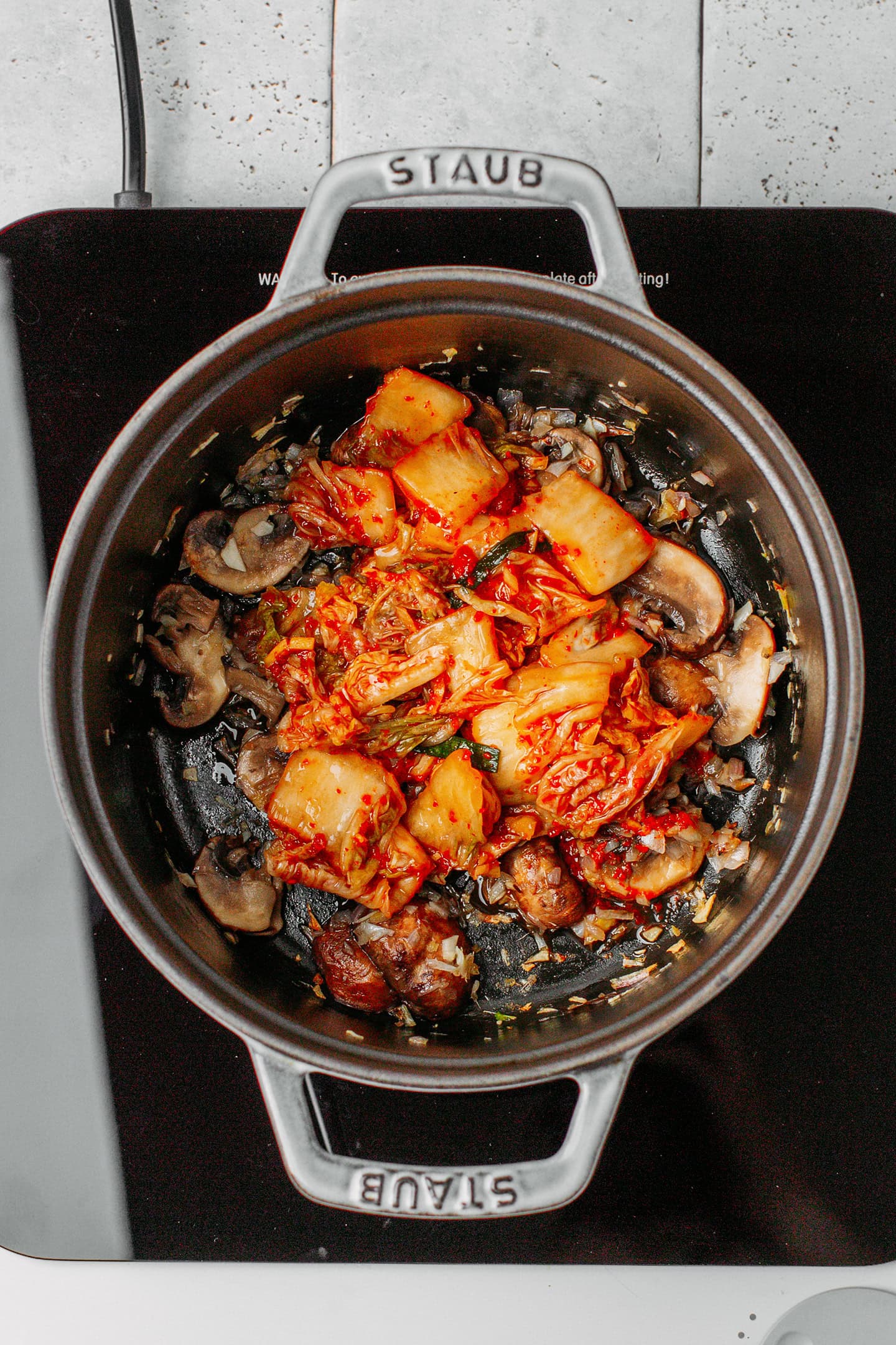 Saut&eacute;ed mushrooms and kimchi in a pot.