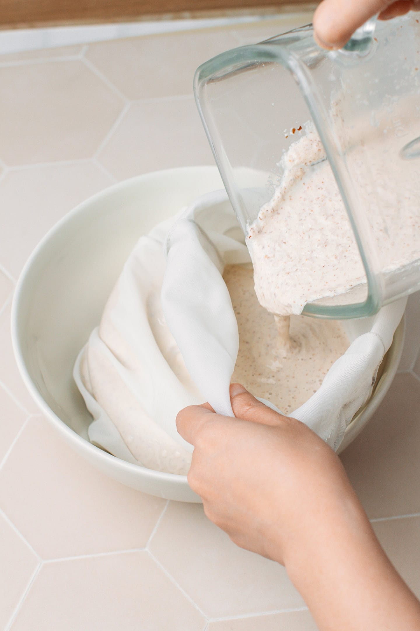 Pouring unfiltered almond milk into a nut milk bag.