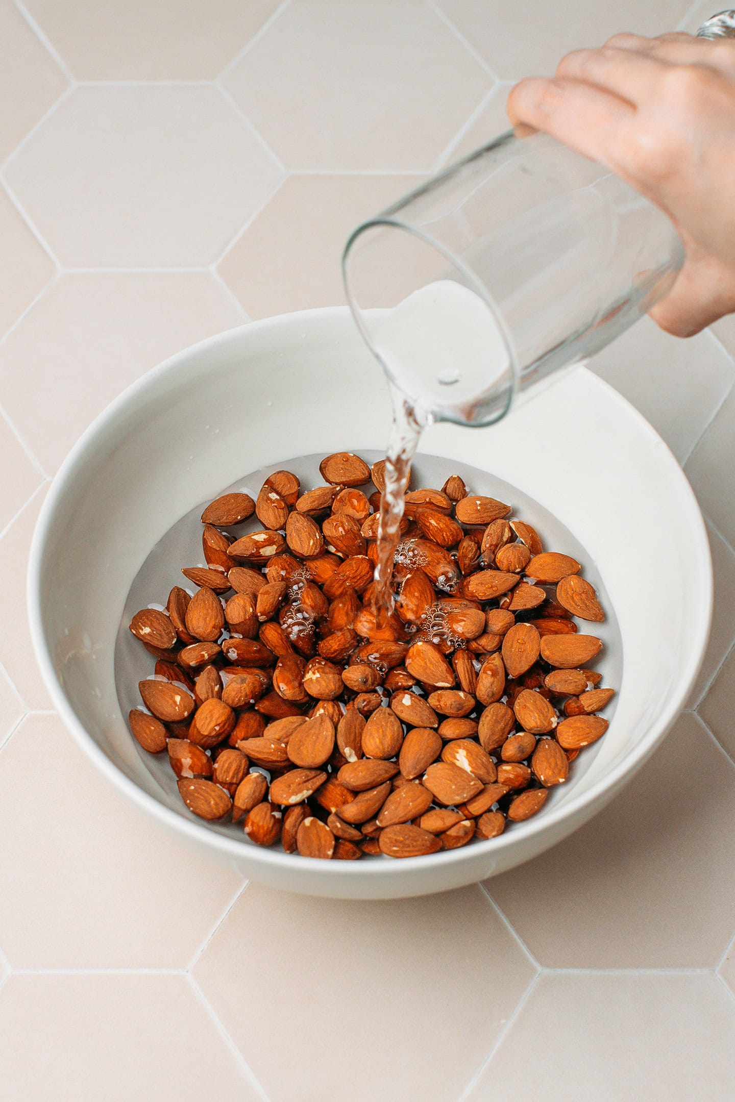 Pouring water over raw almonds in a bowl.