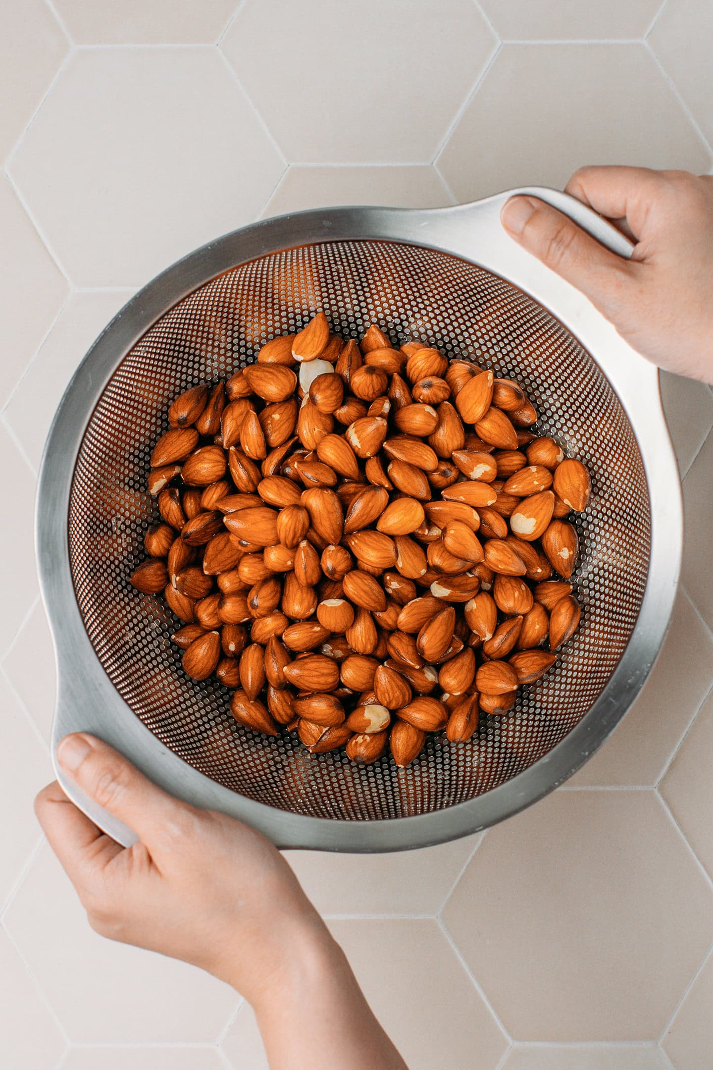 Draining soaked almonds using a colander.