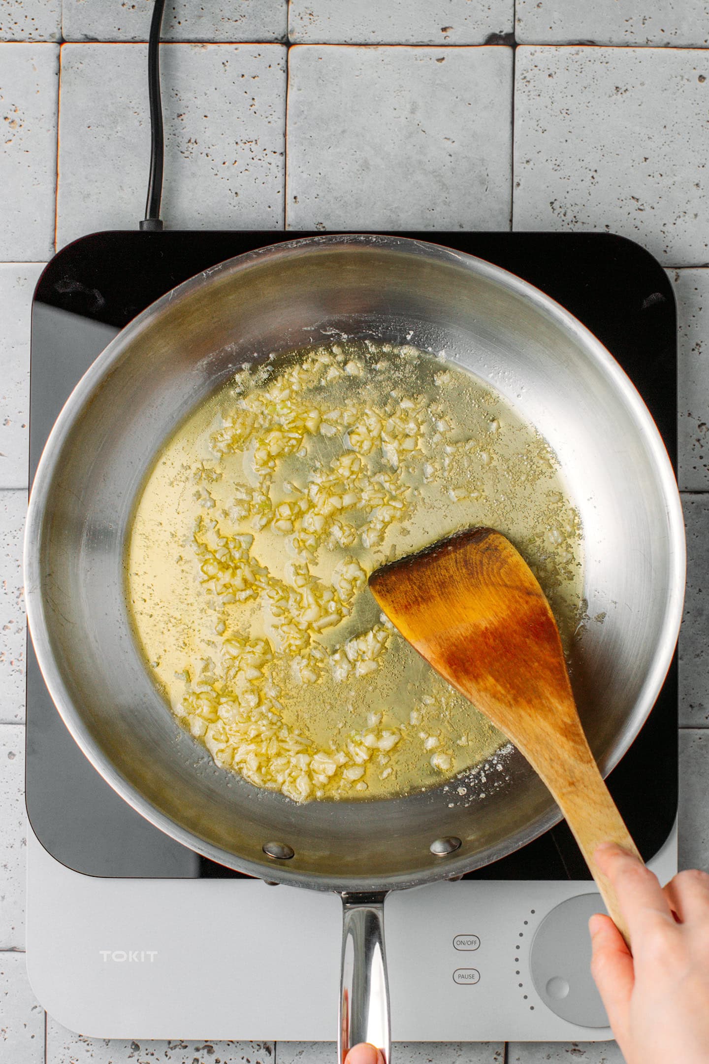 Stirring minced garlic in a skillet.