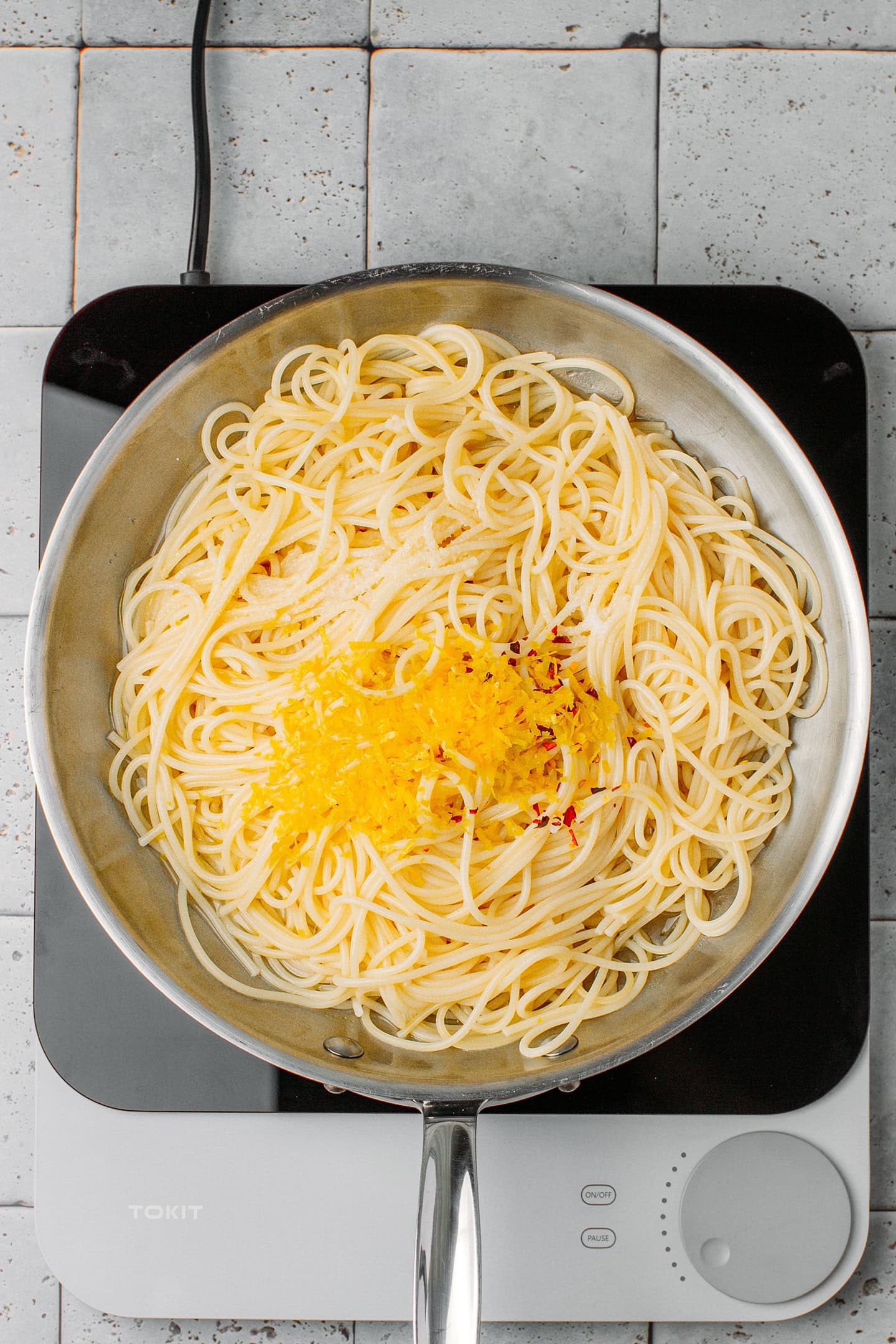 Cooked spaghetti, lemon juice, and lemon zest in a skillet.