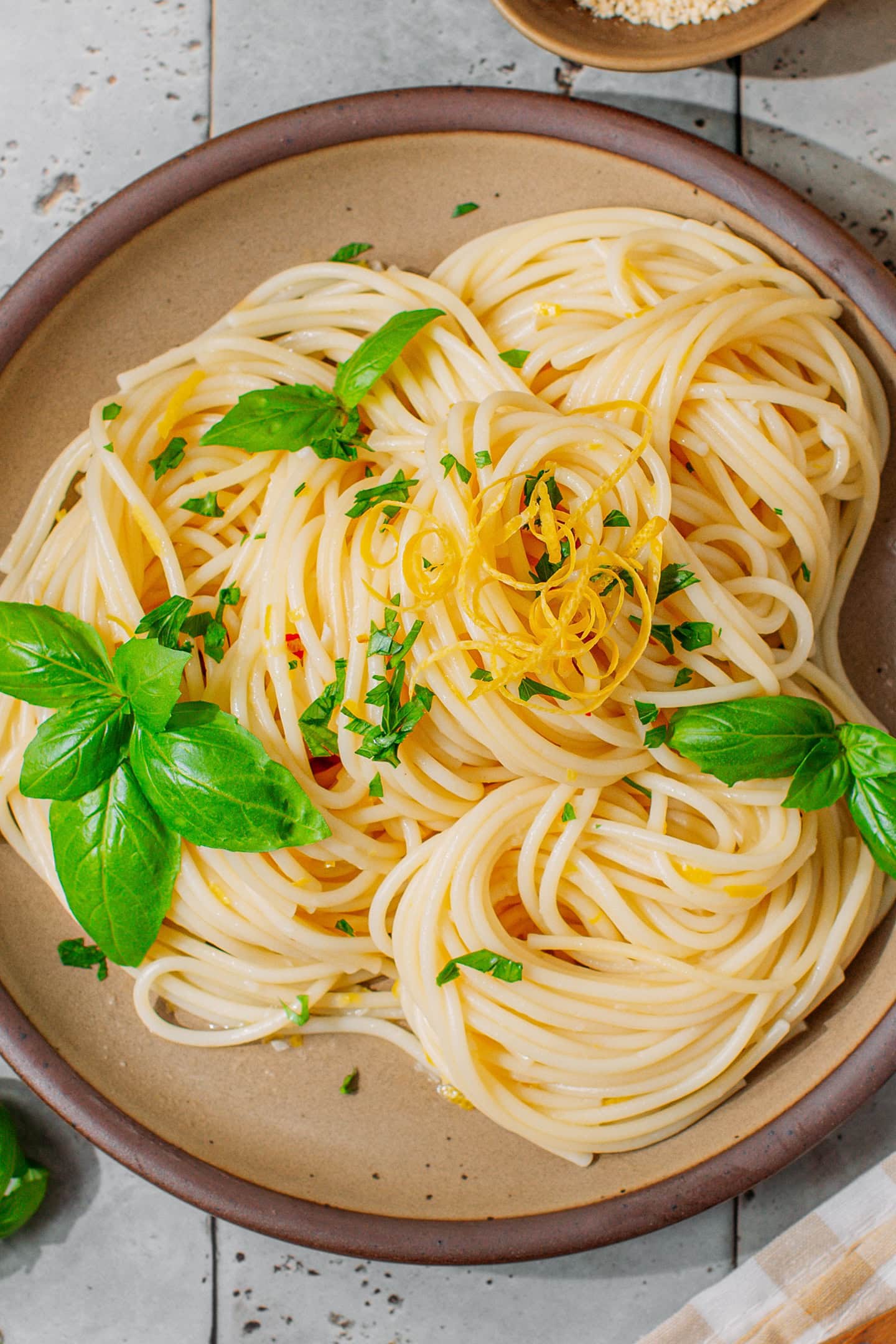 Top view of lemon pasta topped with fresh basil leaves and lemon zest.